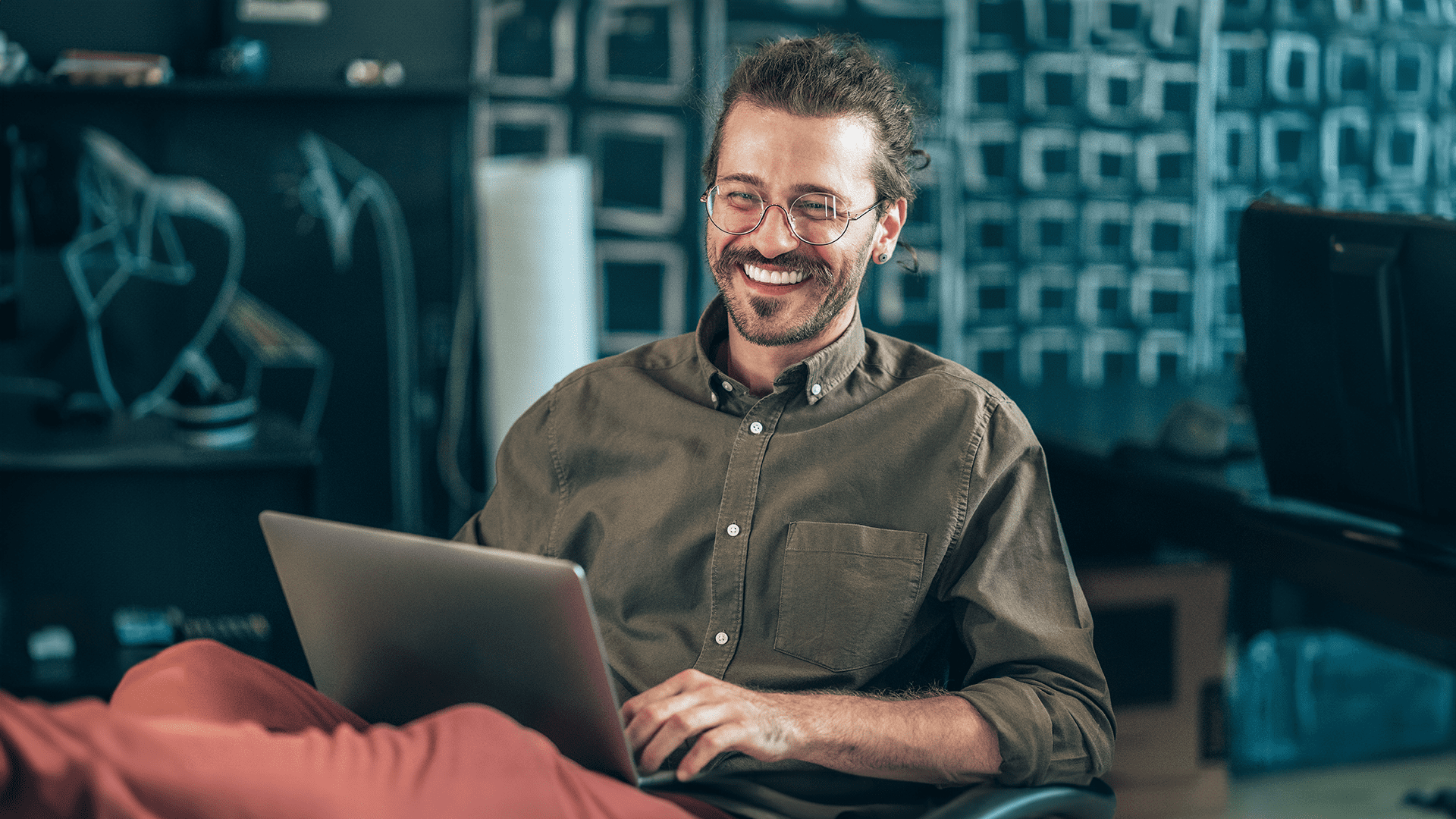 Happy guy sitting at his desk working as a senior cyber security analyst