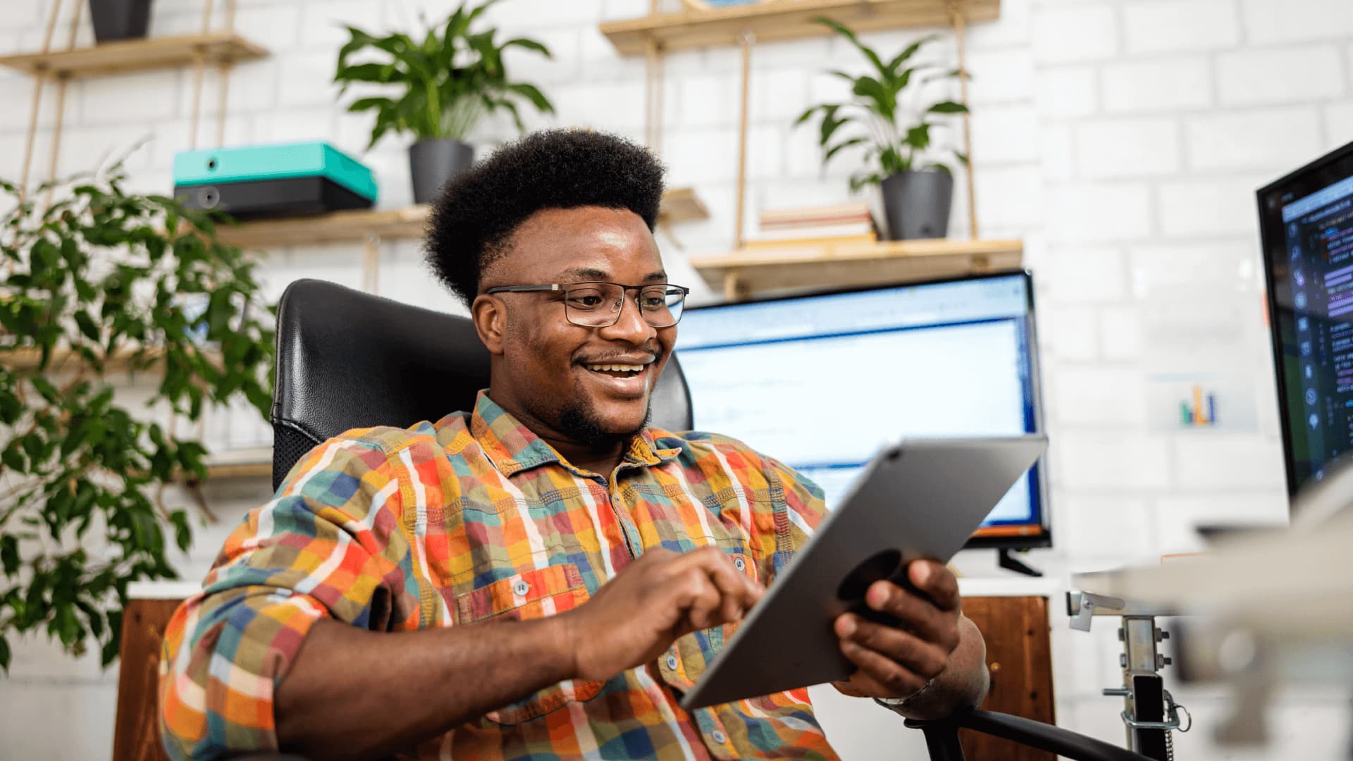 Guy wearing a colourful shirt holding his ipad and testing software applications