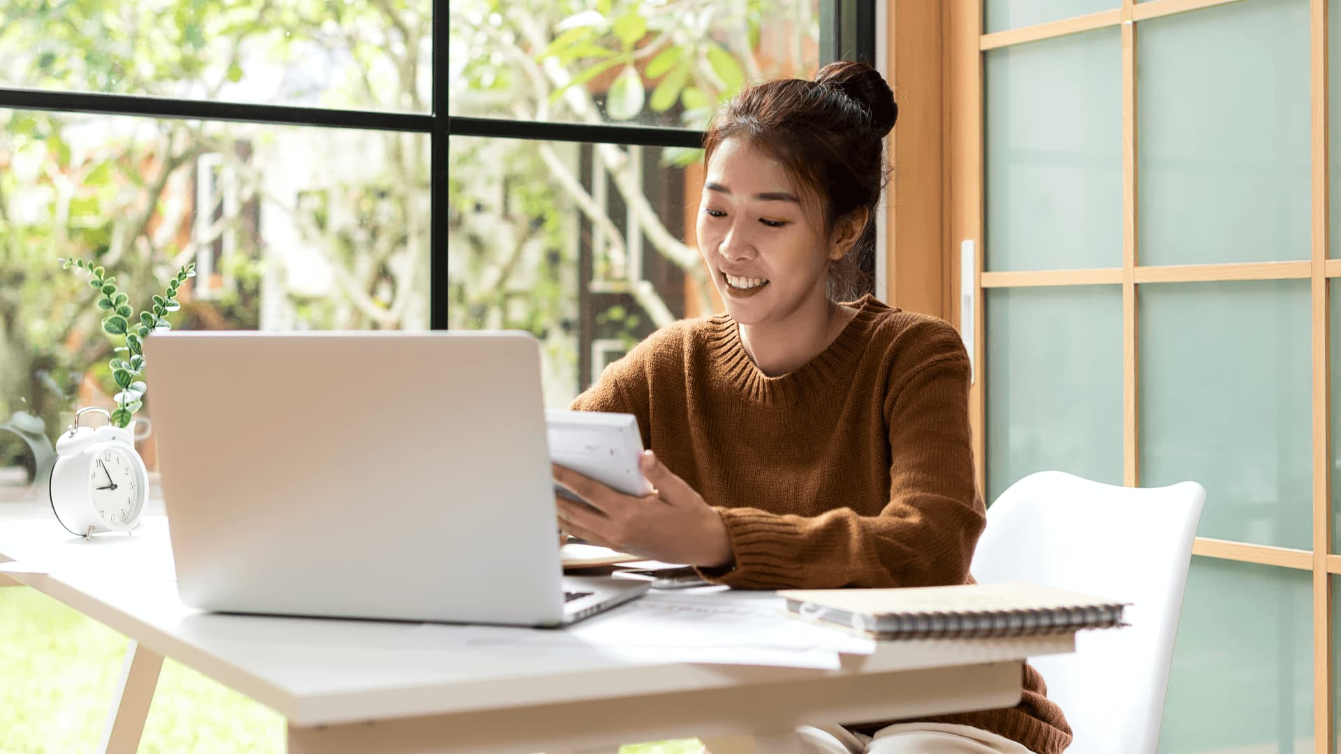 Woman in brown jumper at home doing research for universities with mba rankings