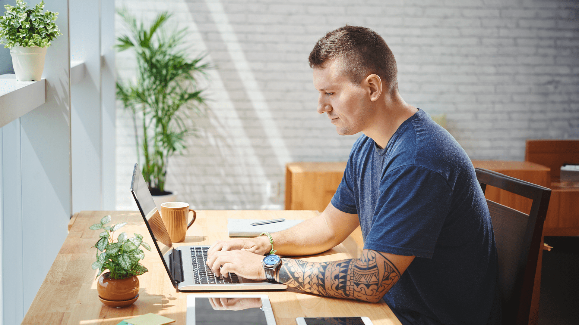 UX designer man with arm tattoo and navy t-shirt working on online software development