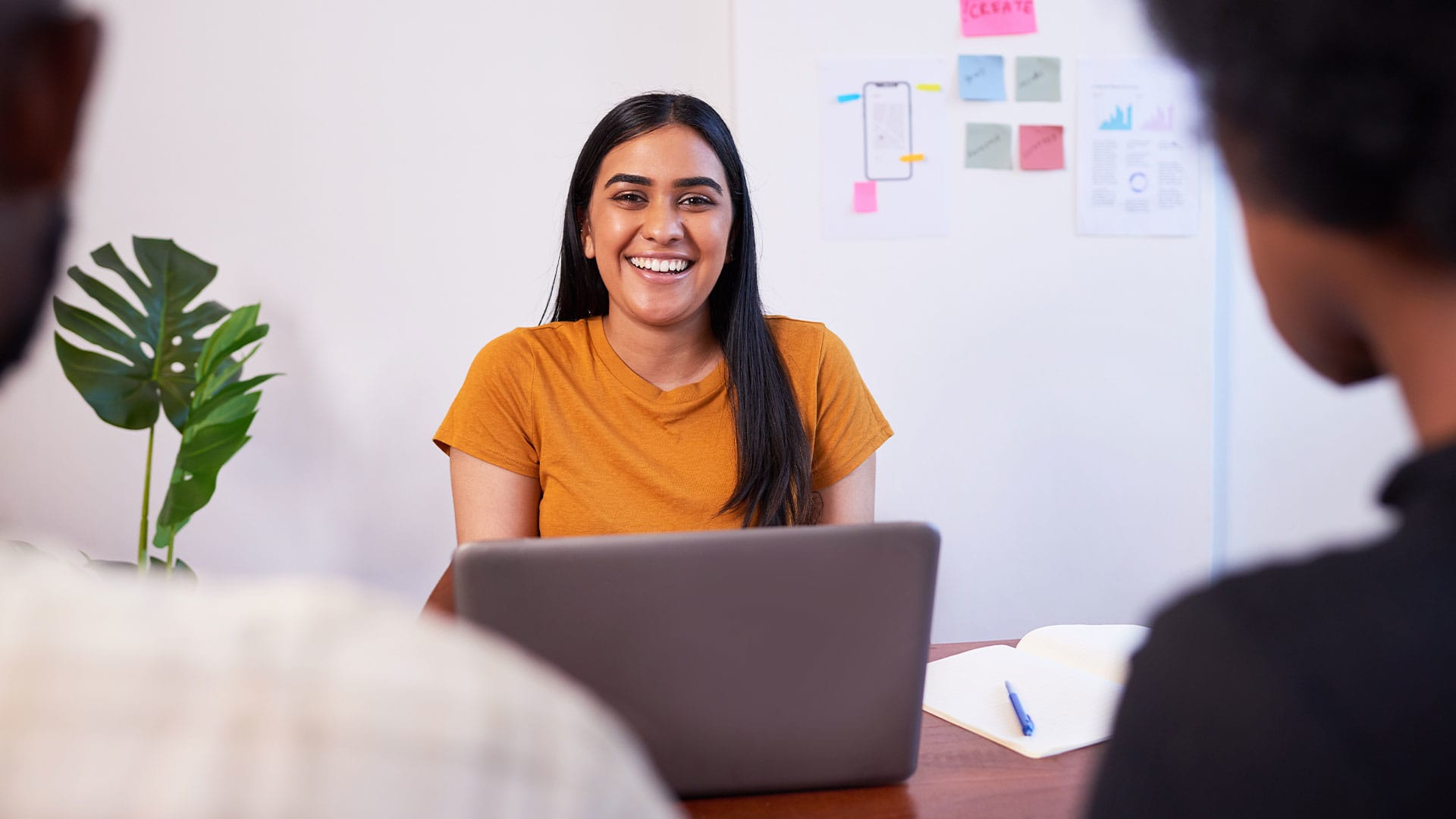 A young woman sitting and smiling with her laptop.