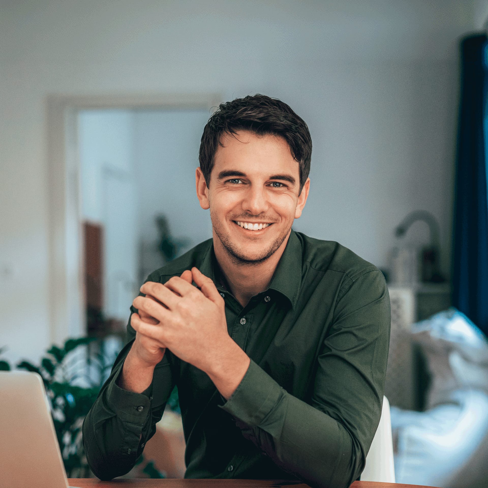 Man in green shirt at laptop searching for career opportunities in business management.