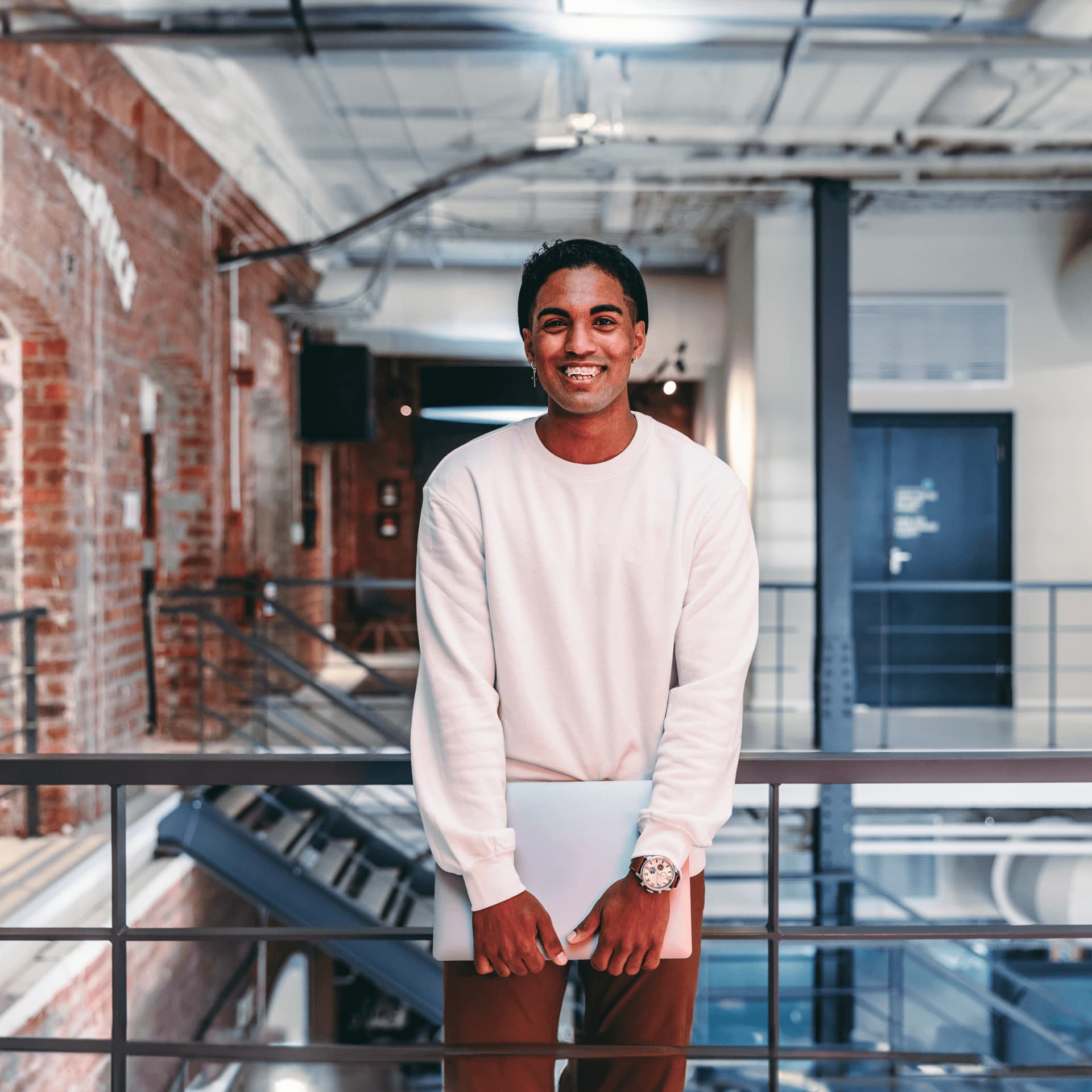 Smiling man holds laptop in office where he works on data management solutions for enterprise data.