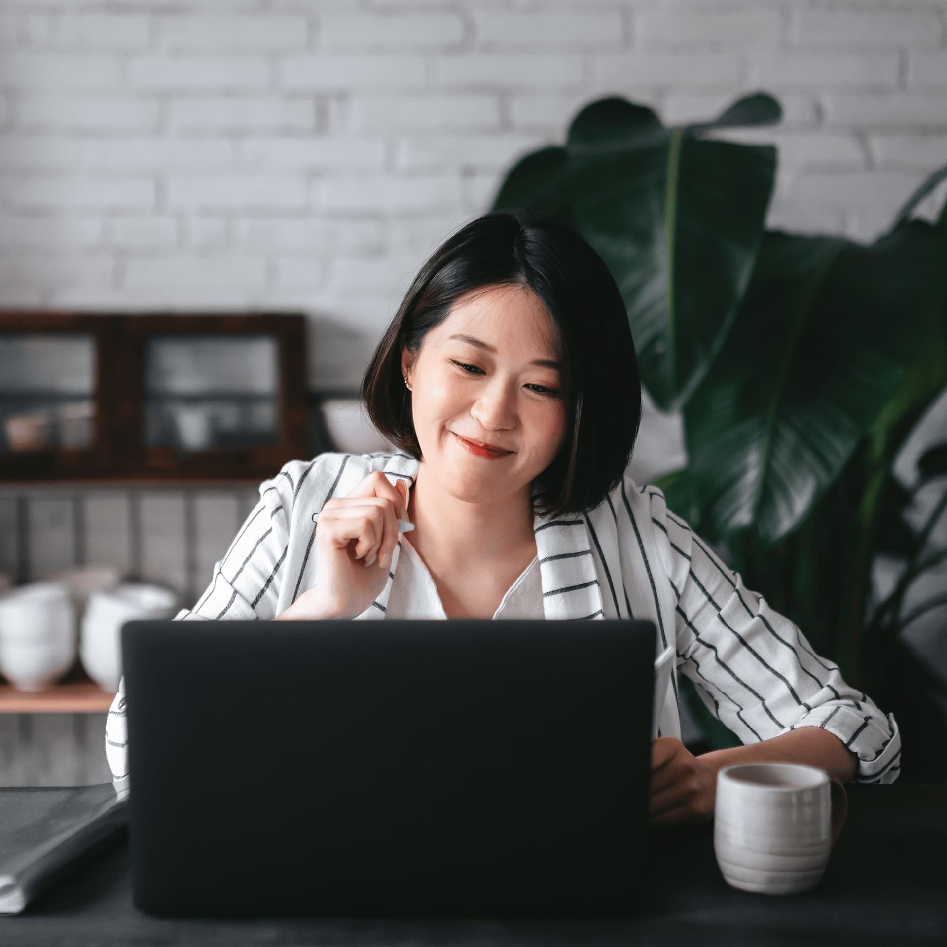 Woman in striped shirt using laptop to research foundation study.