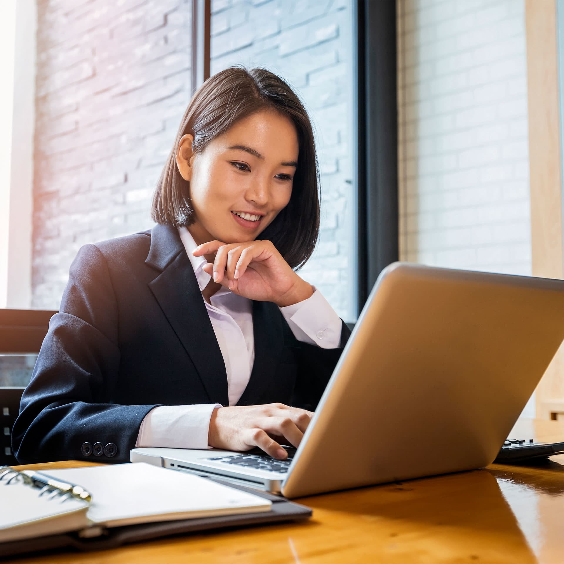 A young woman looking at her laptop and smiling.