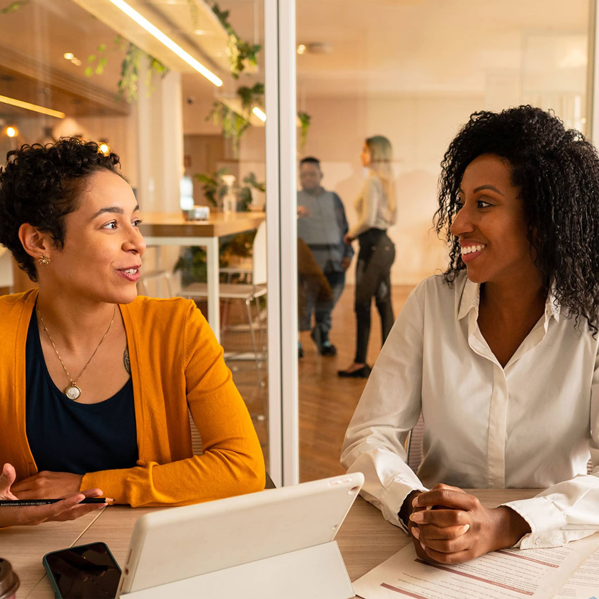 Two women in the office talking and smiling.