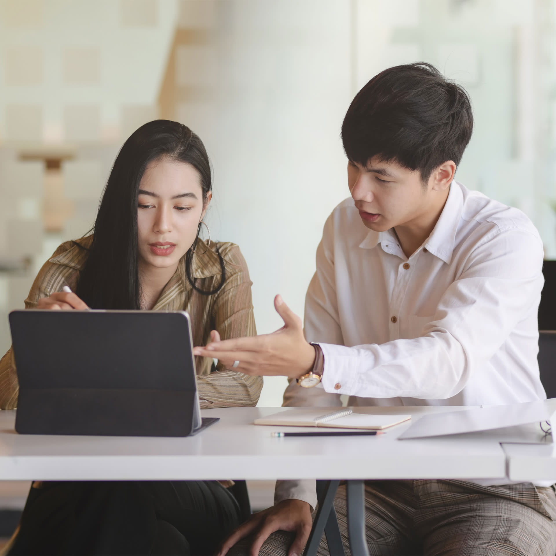 A man and woman in a meeting looking at an ipad.