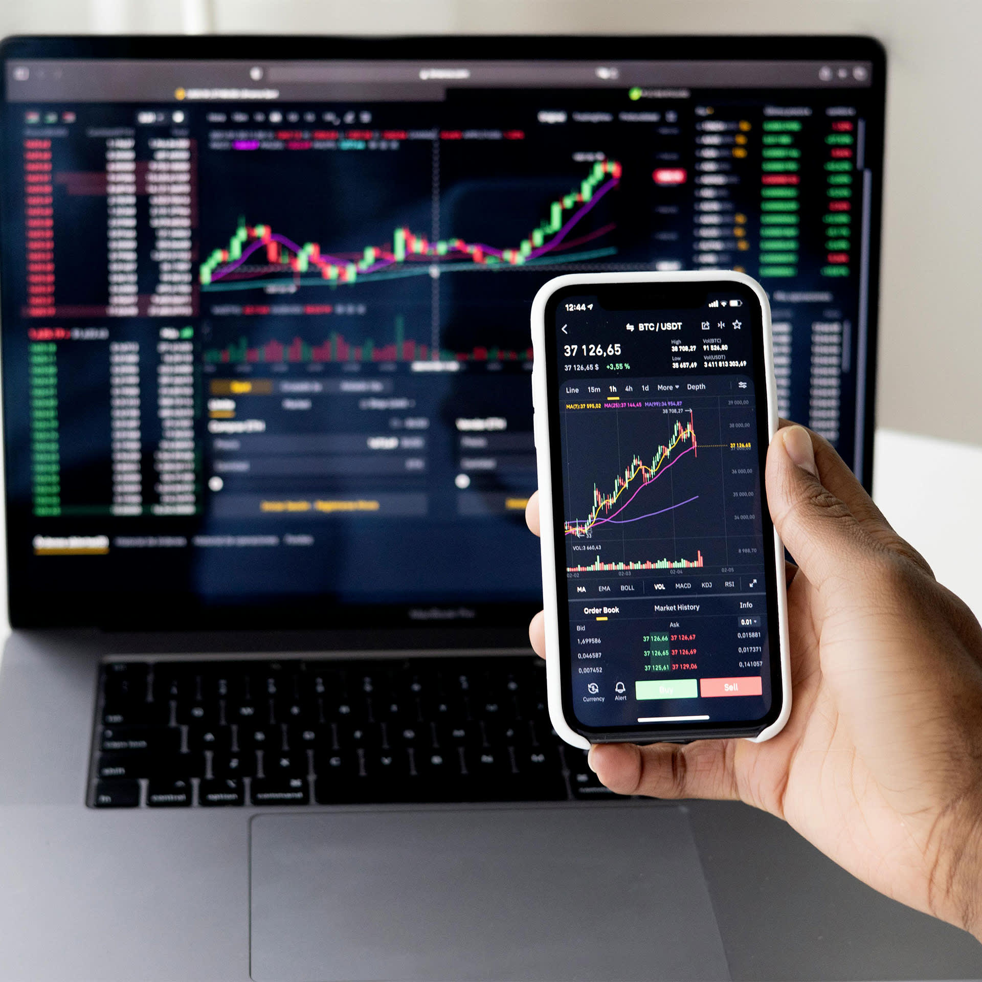 A computer and a phone showing the stock market.