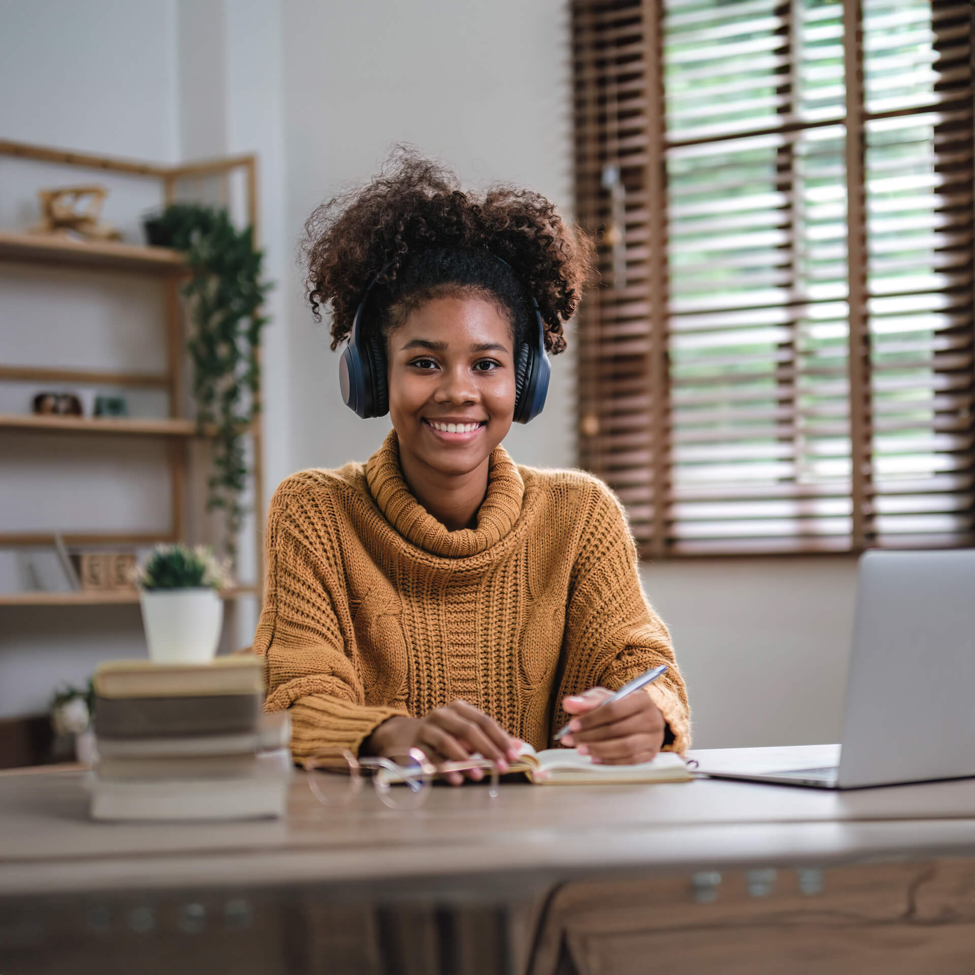 Happy girl sitting at a desk with her headphones studying for her online bachelor in AI