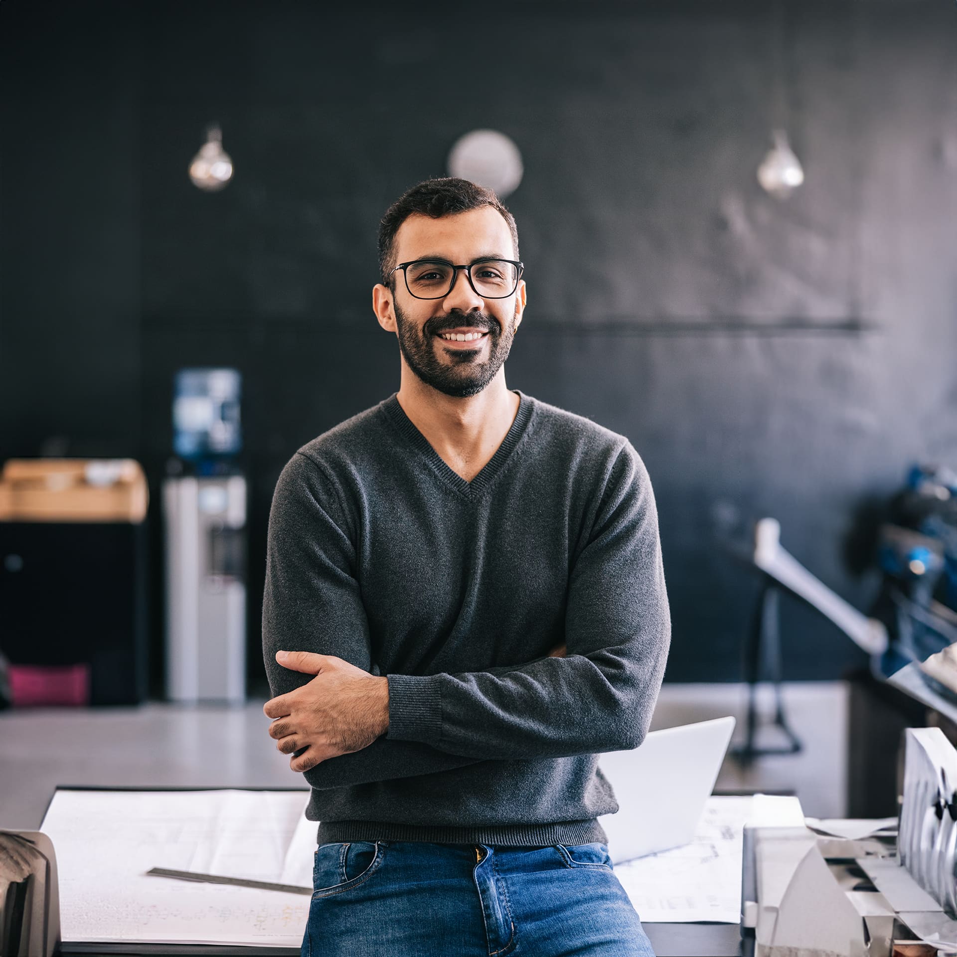 Guy with glasses wearing a grey blouse is happy to get his online master degree in cyber security