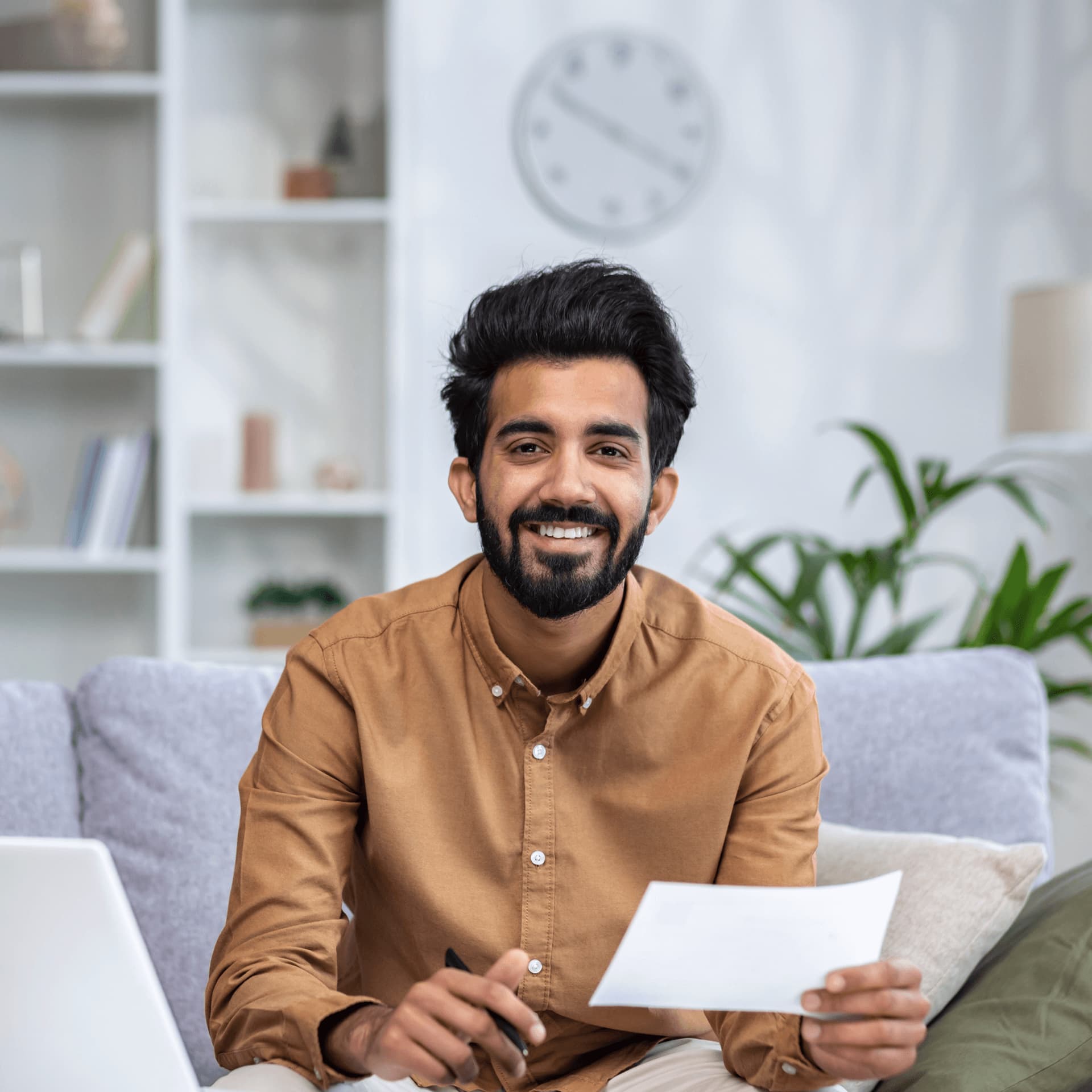 Male business psychology masters student in brown shirt happy to work from online resources.