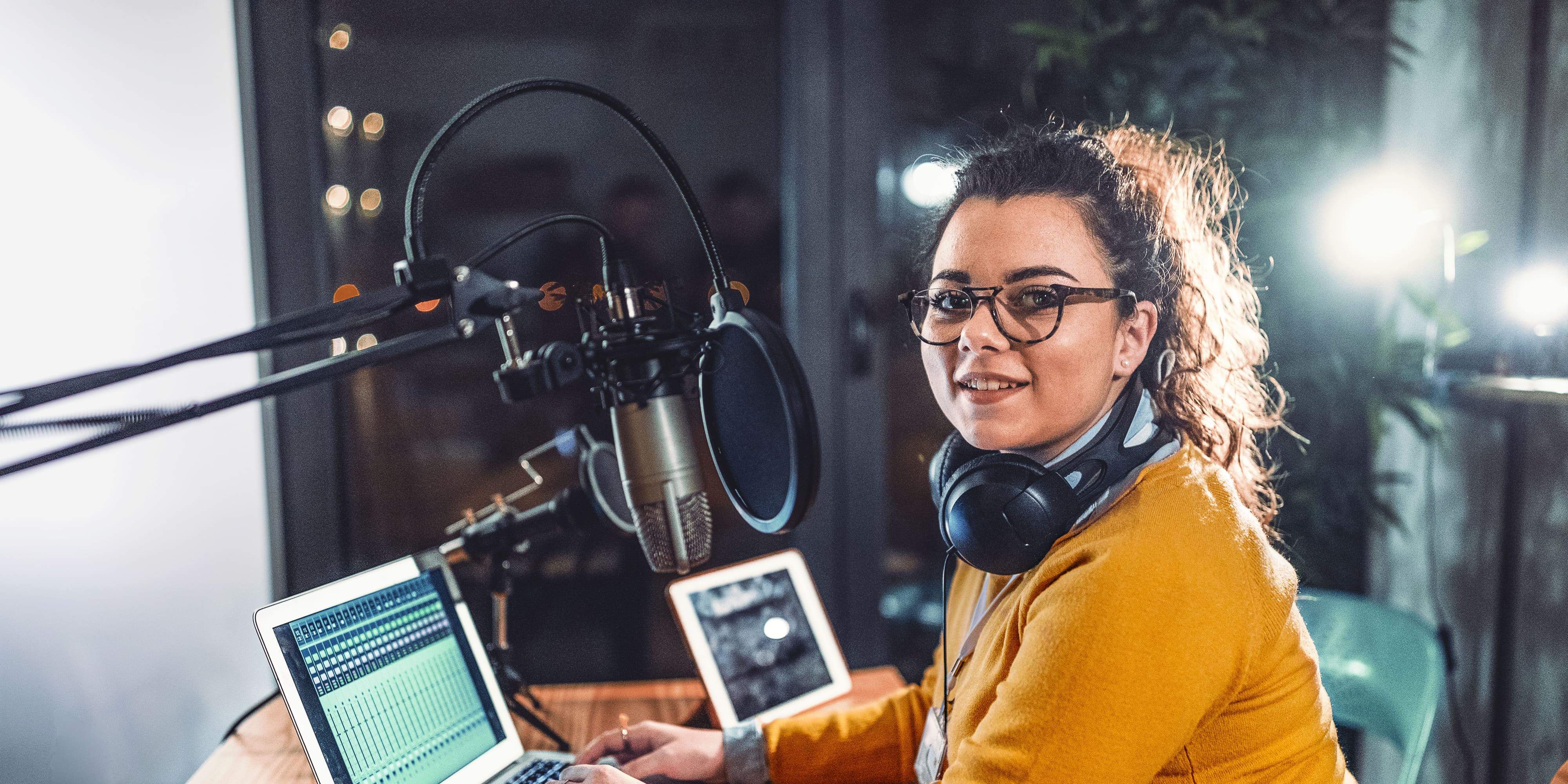 Titelbild für Infoseite “duales Studium Kommunikation und PR": Studentin mit Kopfhörern im Aufnahme-Studio