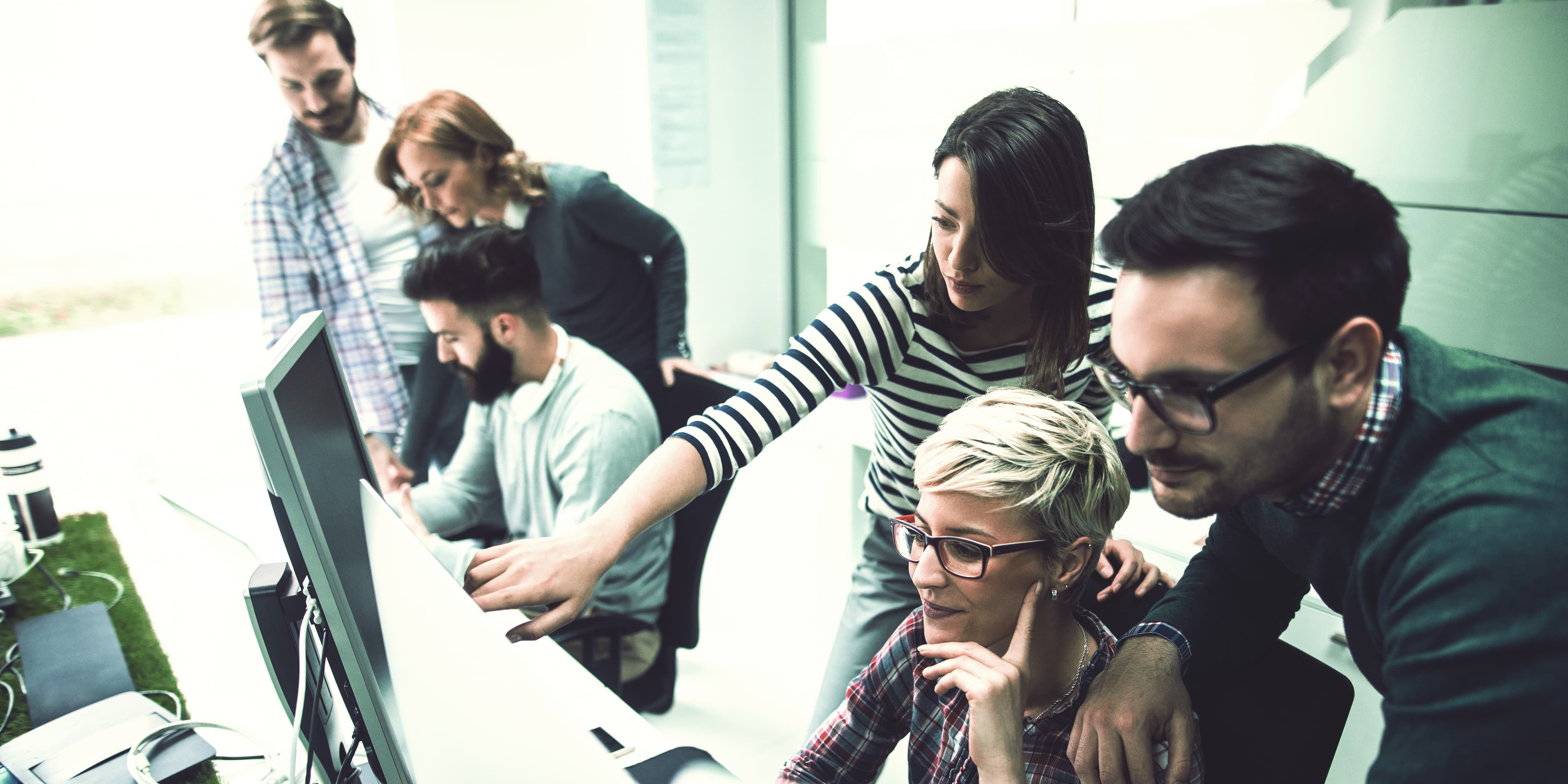 Team bei der Problemlösung vor Bildschirm im Büro