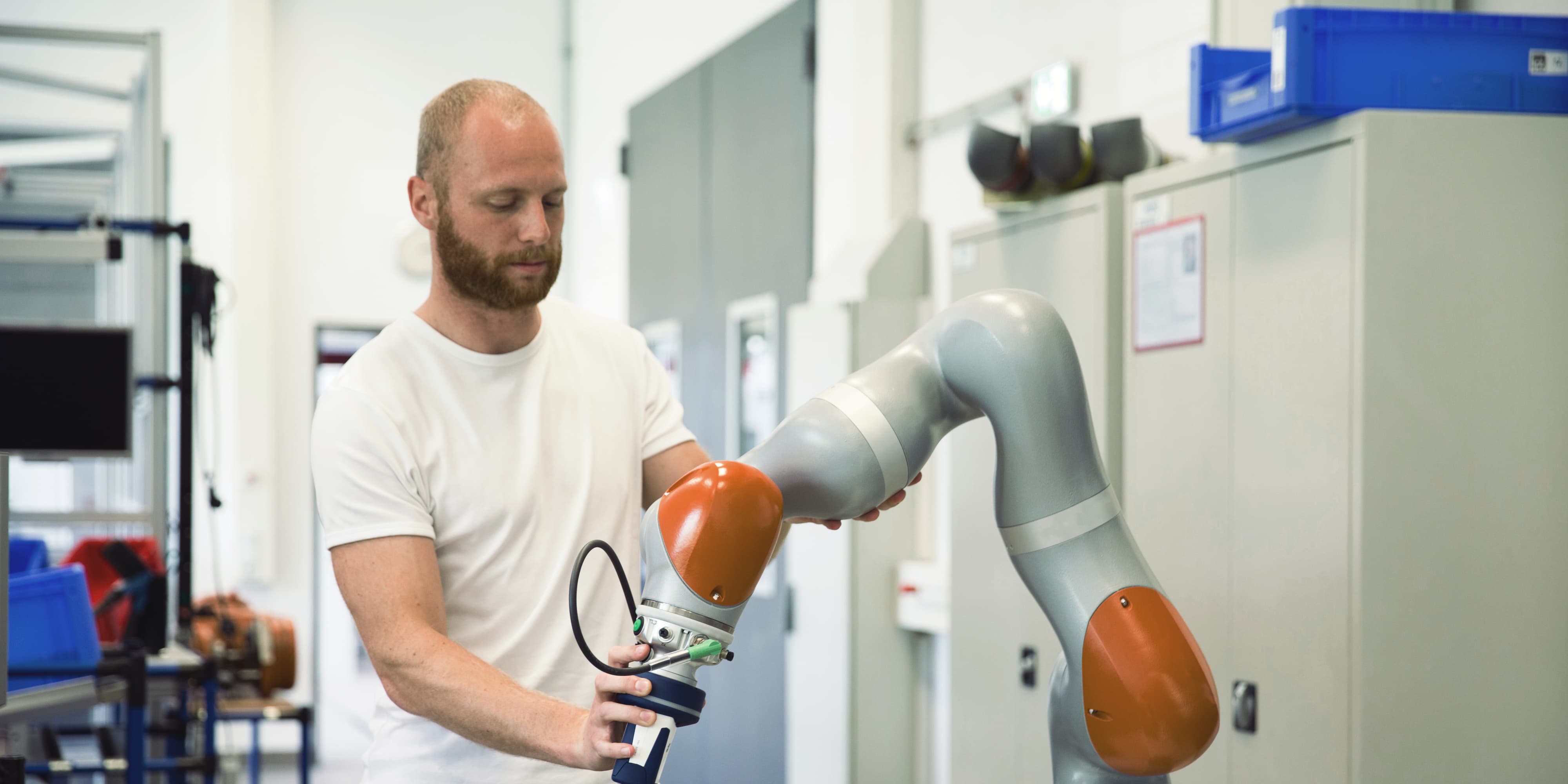 Karrieremöglichkeit “Entwickler:in für Smart Factory”: Student arbeitet an einem Roboter-Modell