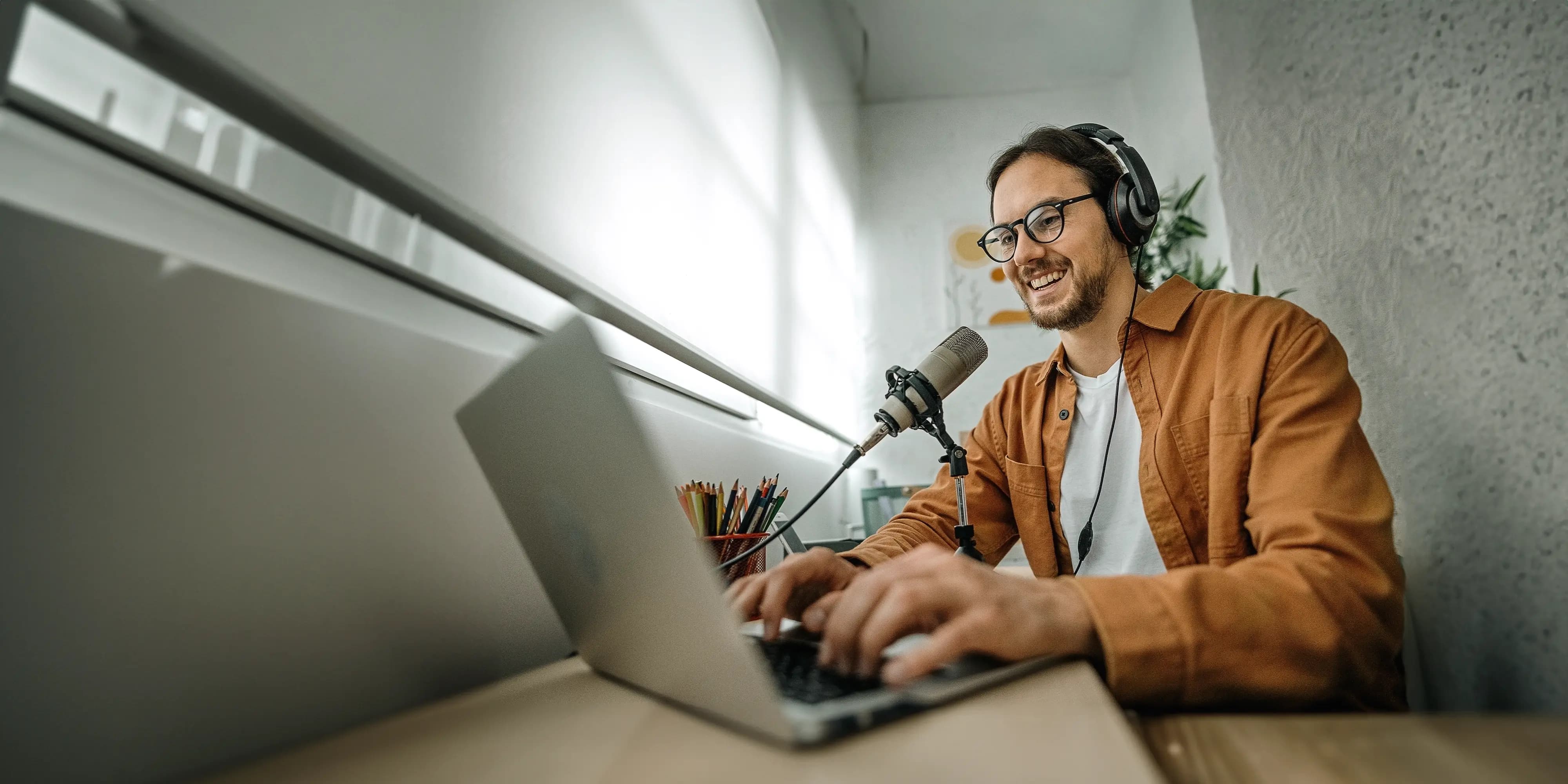 Titelbild der Infoseite "Online-Journalismus-Studium": Studierender nimmt nimmt ein Voice Over am Laptop auf