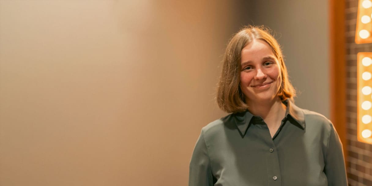 Titelbild zu Artikel "Remote-Arbeit im dualen Studium Online Marketing – Leas Story": Lea Ritter lächelnd im Büro von Schenk Immobilien