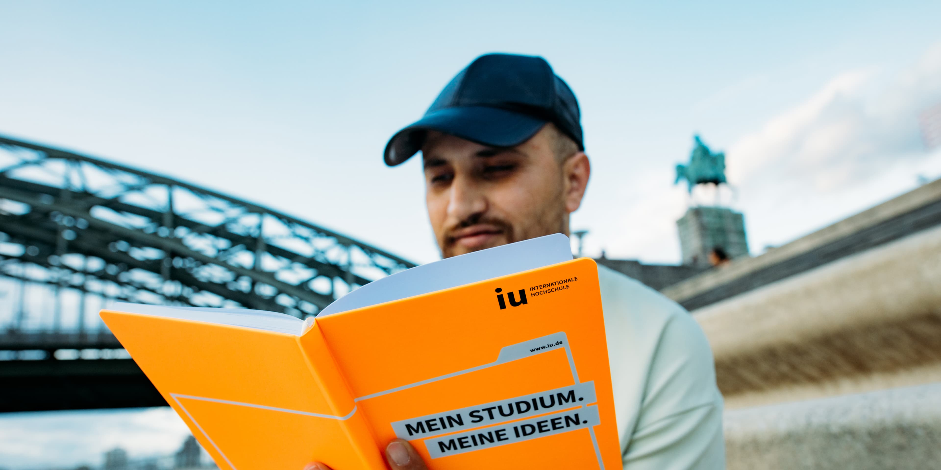 IU student reading his notes in front of a bridge, which is visible in the background.