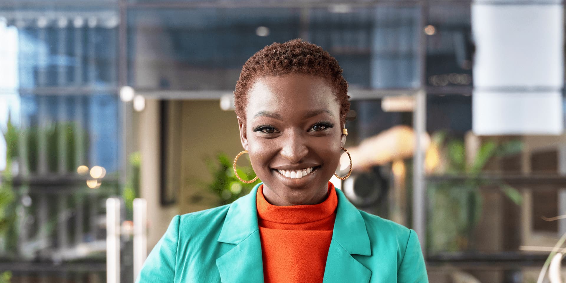 Smiling woman standing outside in formal blazer holding tablet.