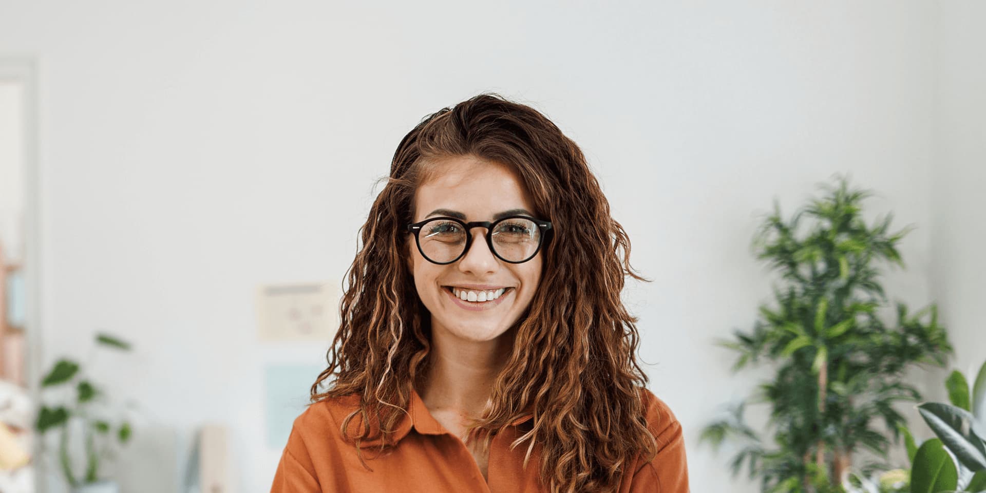 Smiling project manager standing in a home office with arms crossed.