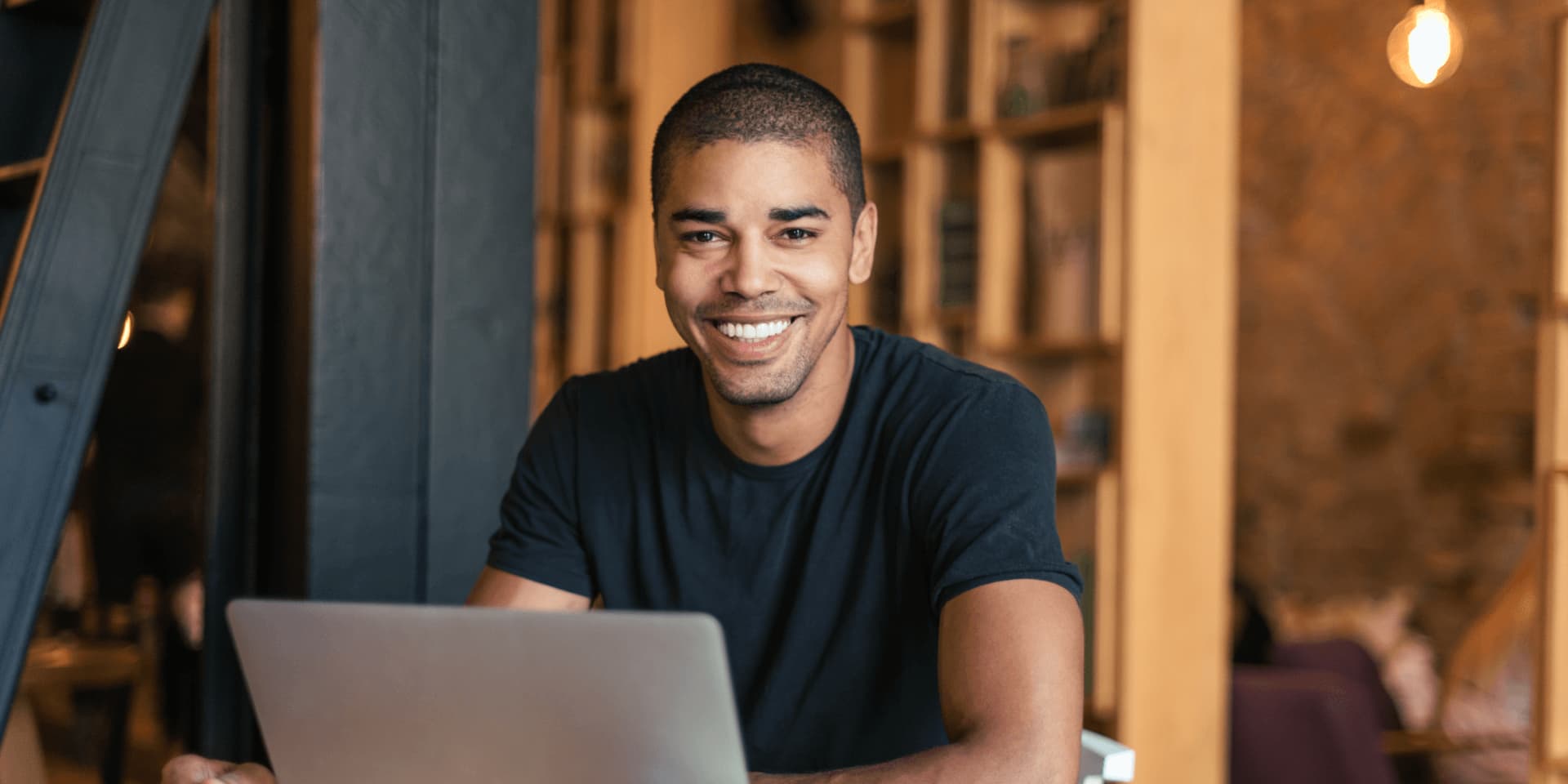 Smiling man finding an affordable online course to reduce how much university costs UK.