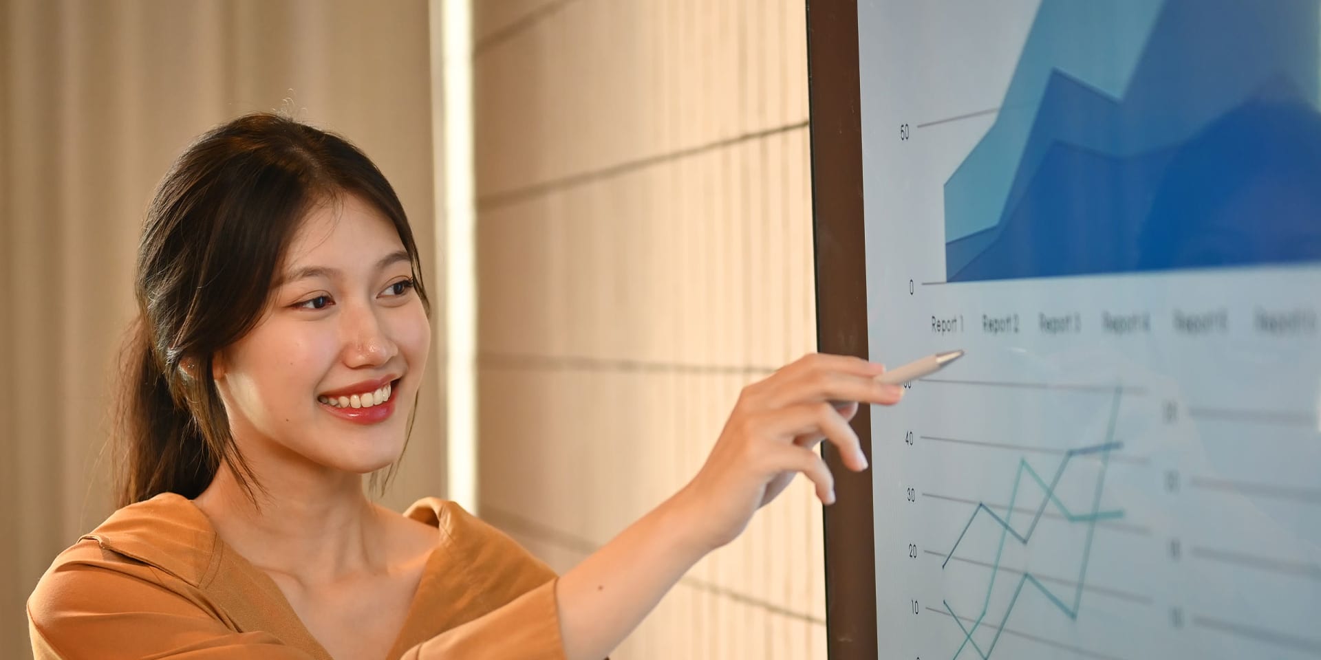 A young woman presenting and pointing at the screen with various graphs.