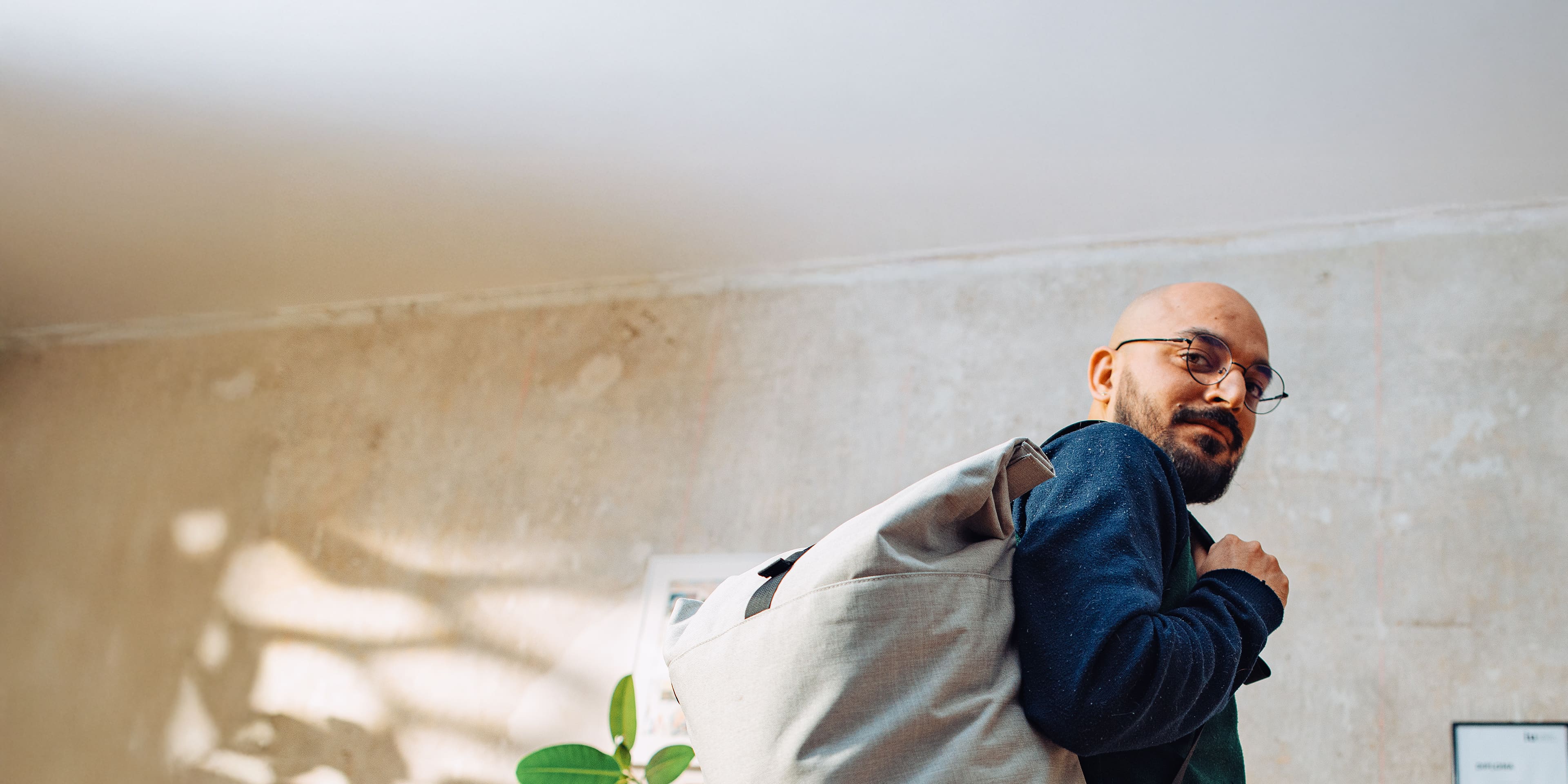 In a bright room, a student is getting ready for classes, carrying a backpack with the logo of IU International University of Applied Sciences