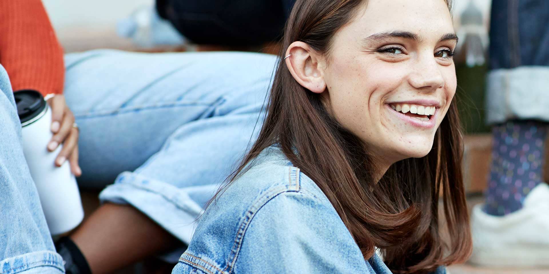 Titelbild zum Artikel "Was machen nach dem Abitur": Abiturientin sitzt mit Freunden draussen