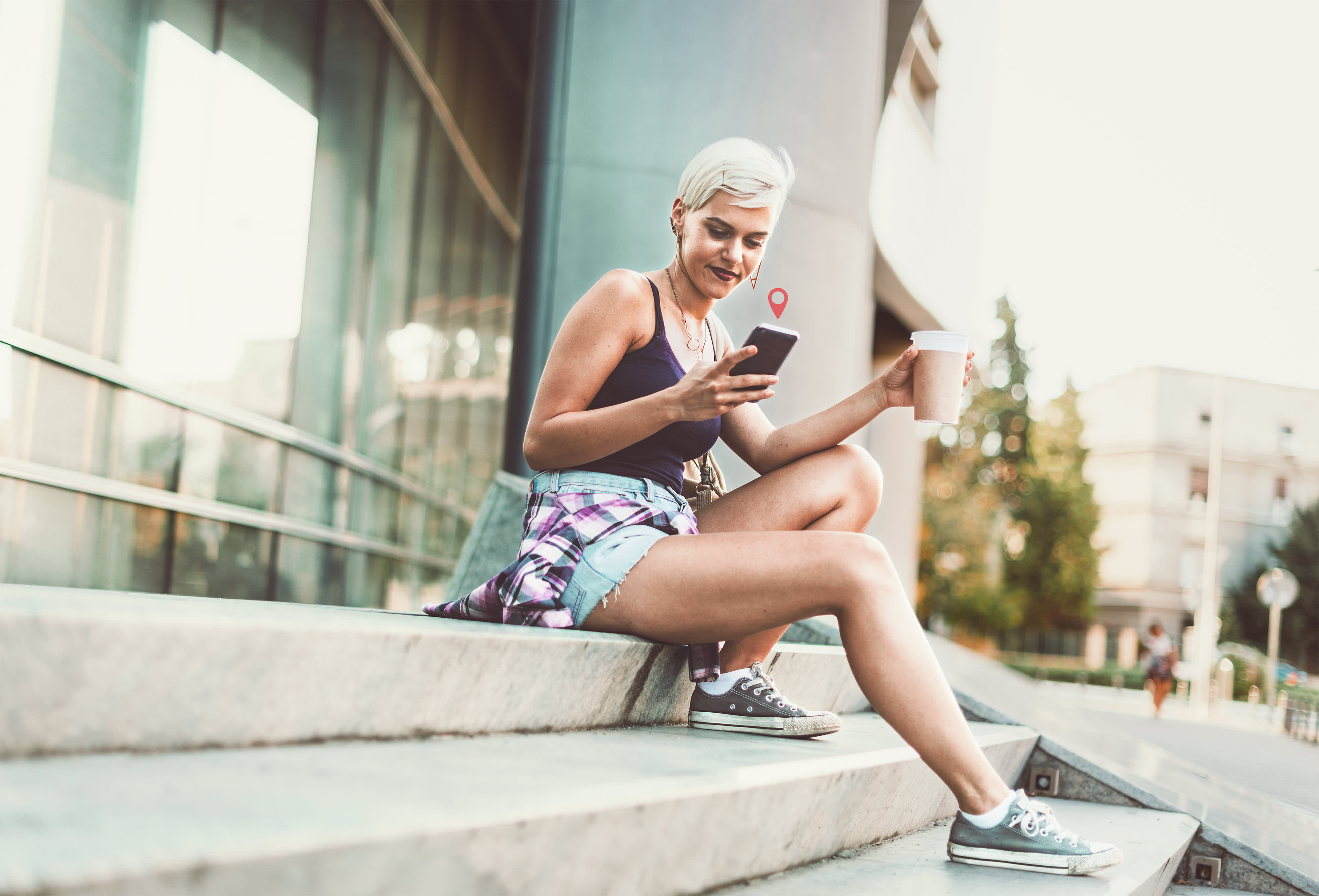 Titelbild für Infoseite “IU Campus”: Studentin mit Smartphone vor dem Campusgebäude