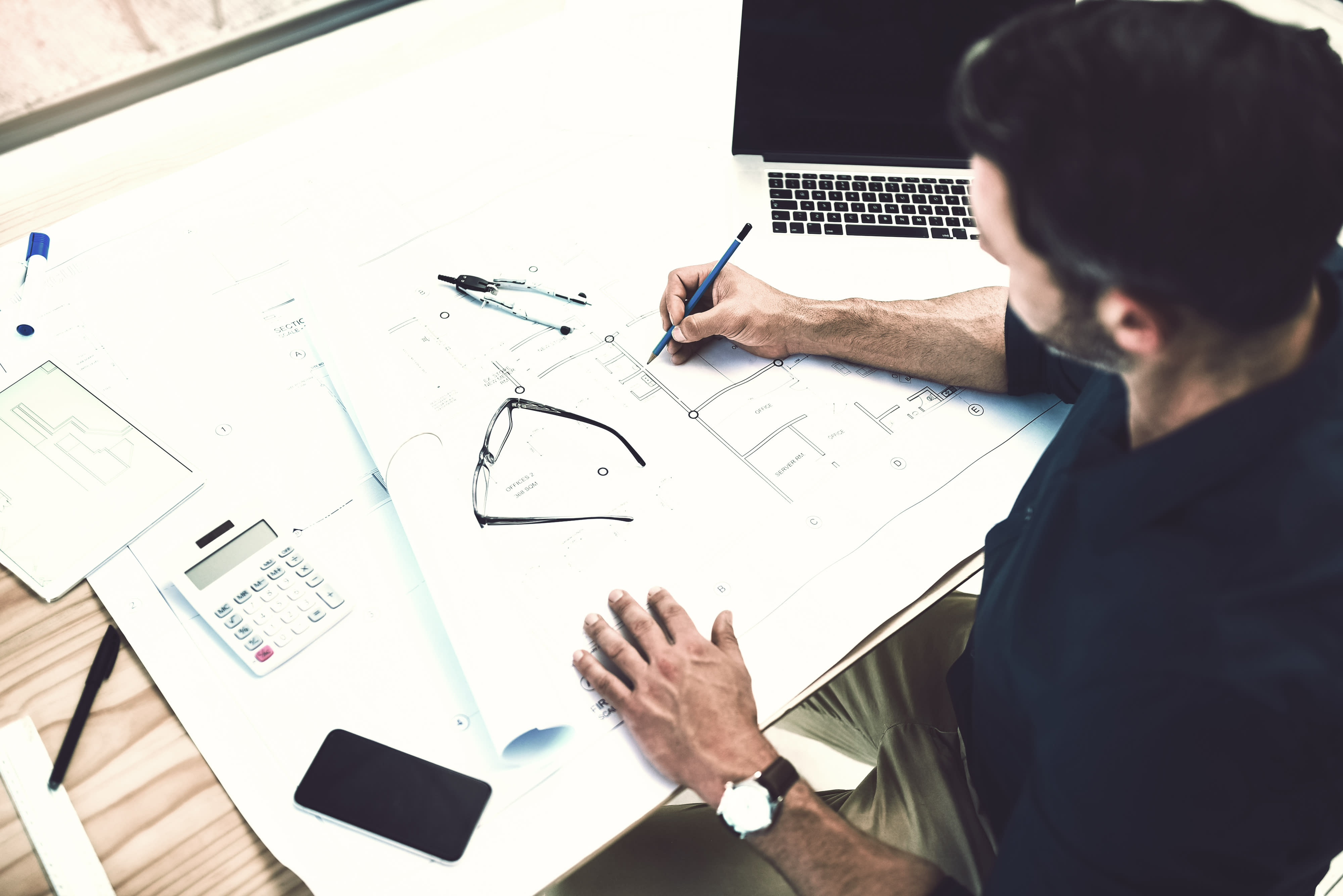 Karrieremöglichkeit “Projektleiter:in in einem Ingenieurbüro”: Mitarbeiter arbeitet an einem Bauplan