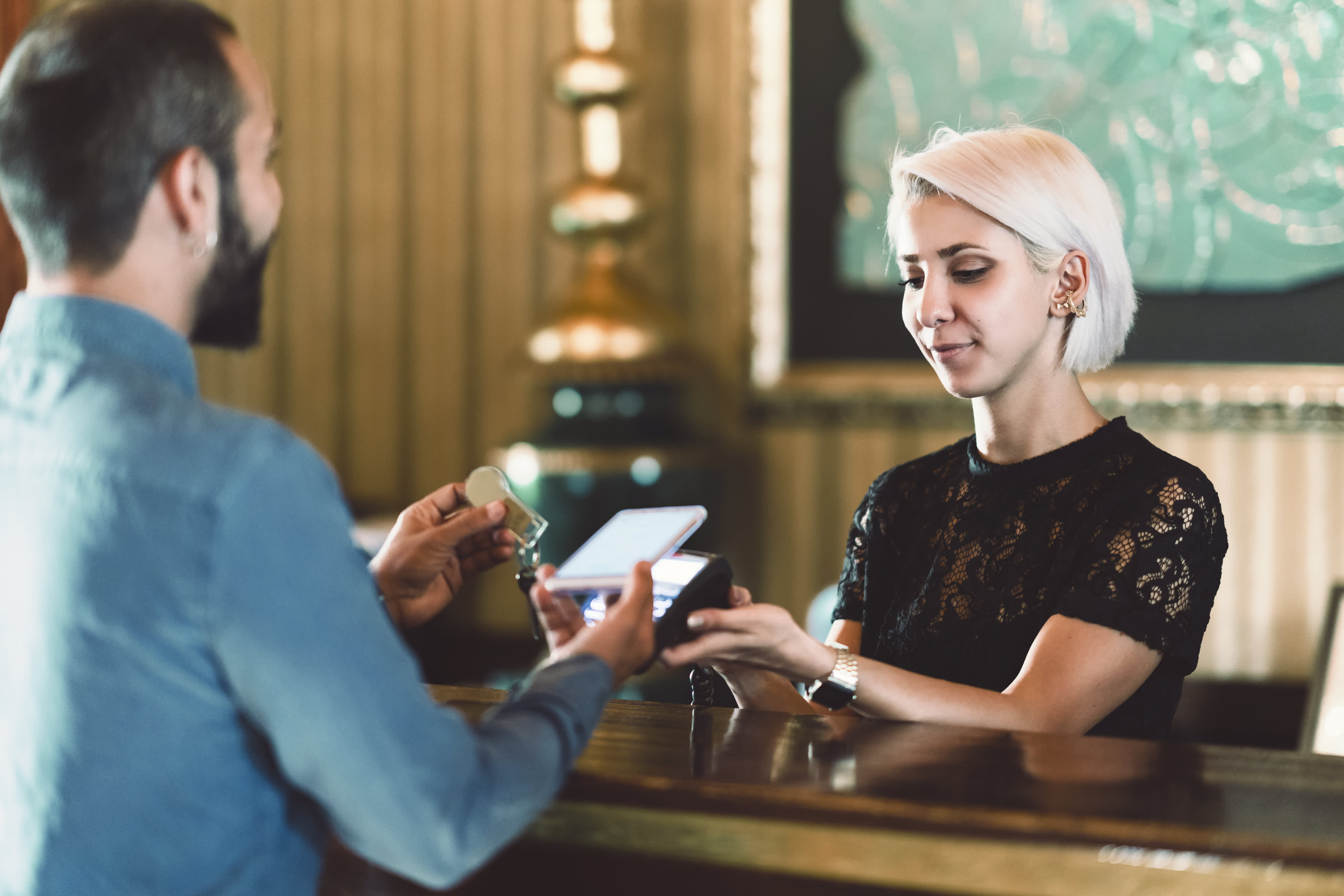 Titelbild für Infoseite “Bachelor Hotelmanagement”: Hotelmanagerin steht an der Hotelrezeption mit Kunden