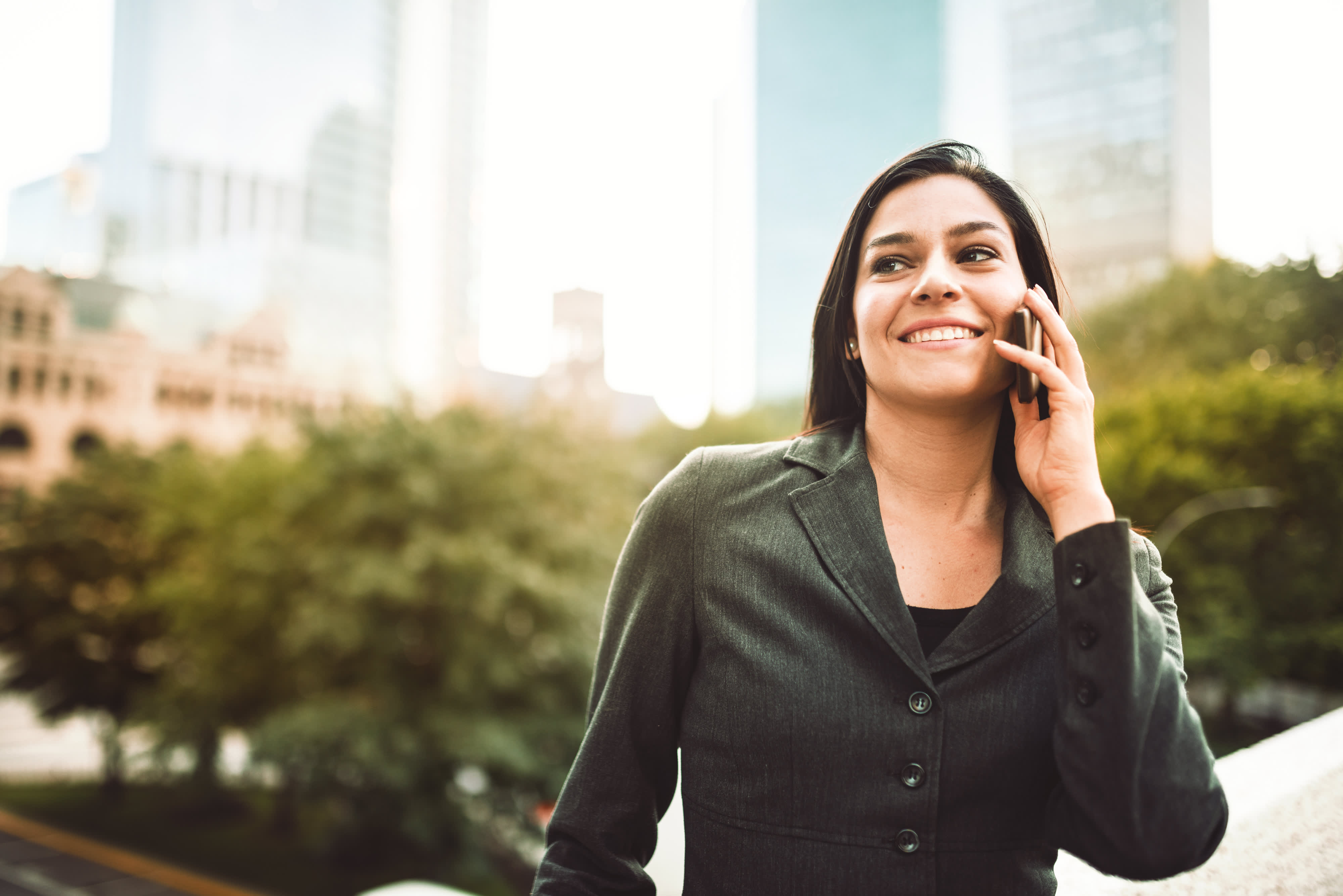 Titelbild für Infoseite “Bachelor Immobilienwirtschaft”: Immobilienmanagerin telefoniert vor Bürogebäude