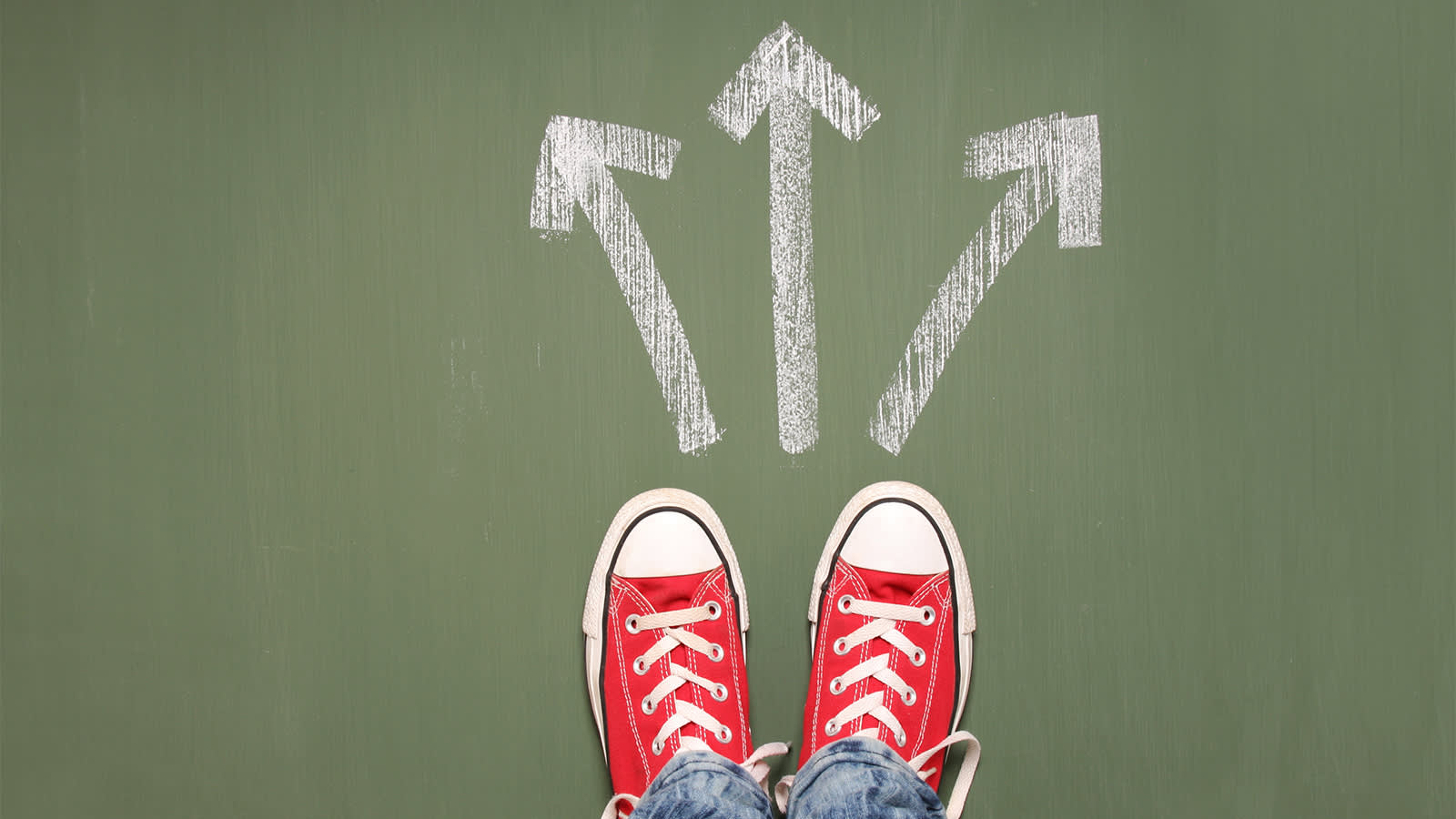 Red sneakers stand at a chalk-drawn crossroads with arrows pointing in multiple directions, symbolizing the decision-making process in choosing a career path.