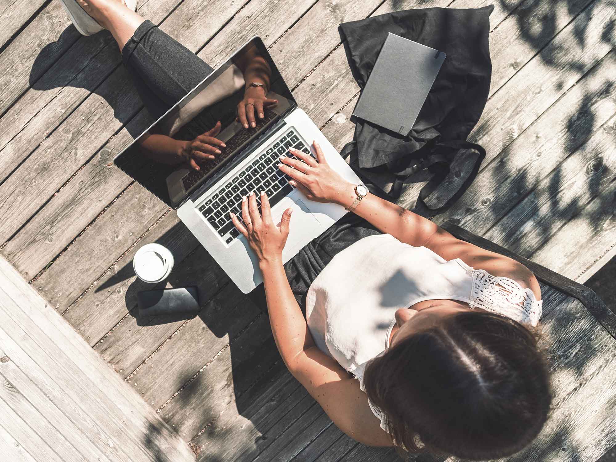 Titelbild für Infoseite “IU Studyfinder”: Studentin mit Laptop auf dem Schoß