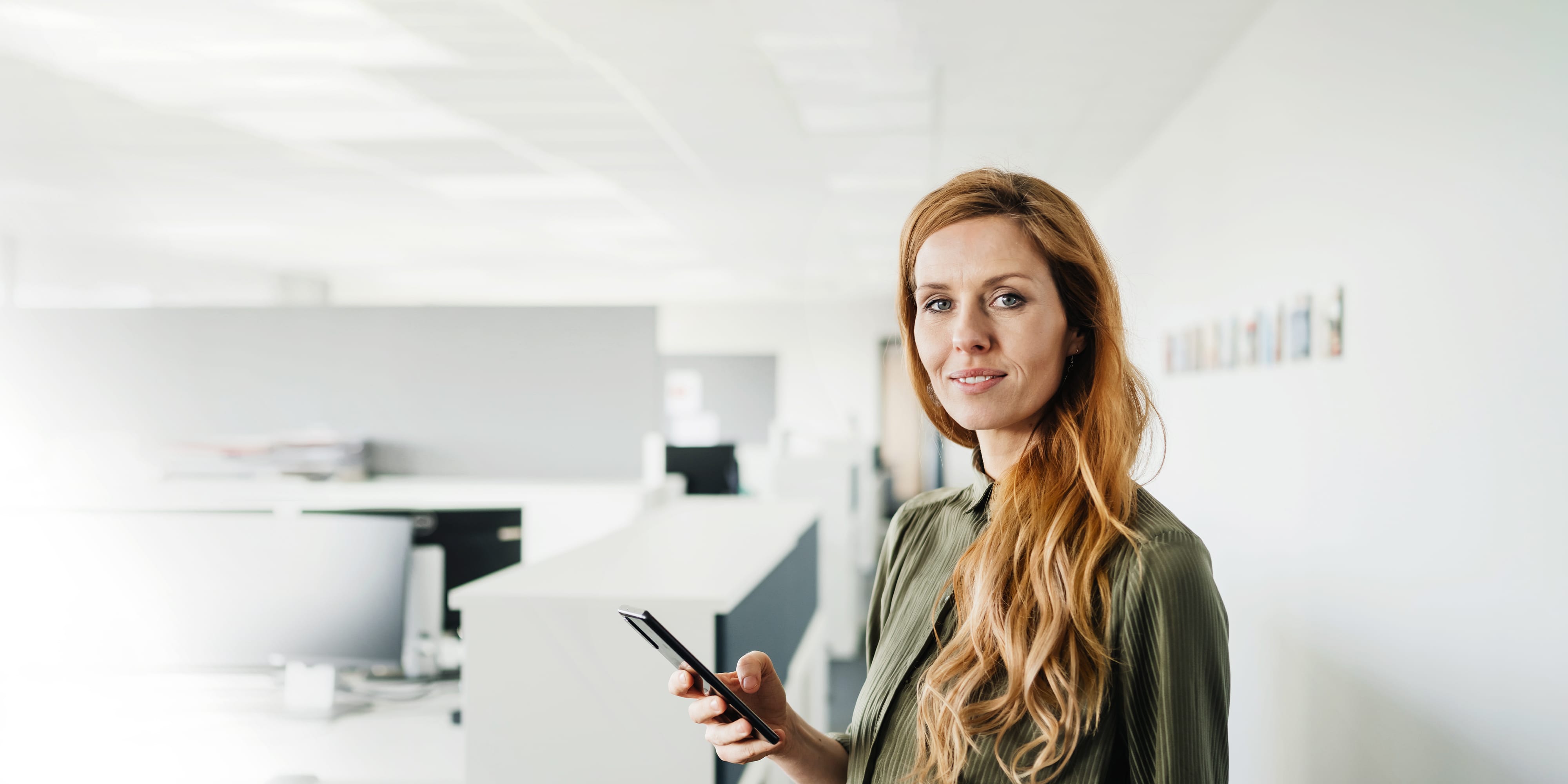 Titelbild für Infoseite "Master ohne Bachelor": Frau mit Smartphone in der Hand im Großraumbüro