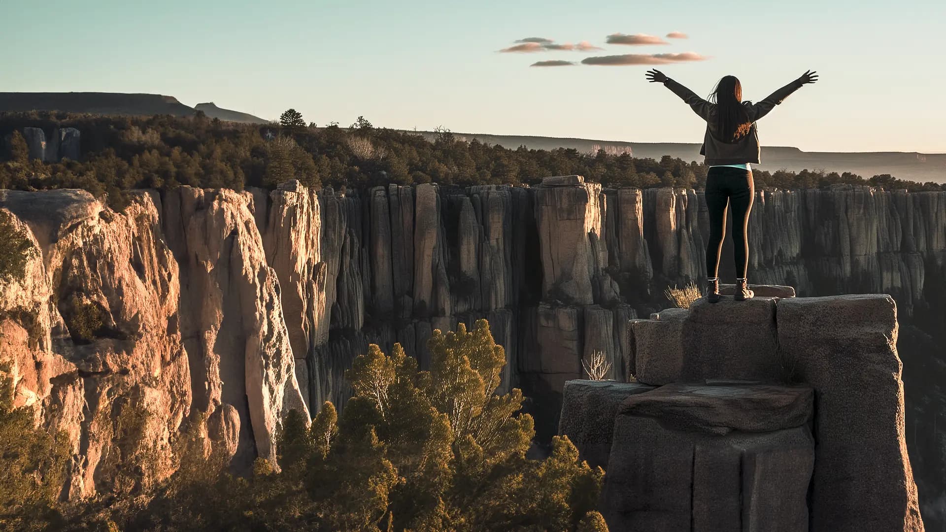 Titelbild zum Artikel "Bucket List": Studentin steht mit offen Armen am Felsen