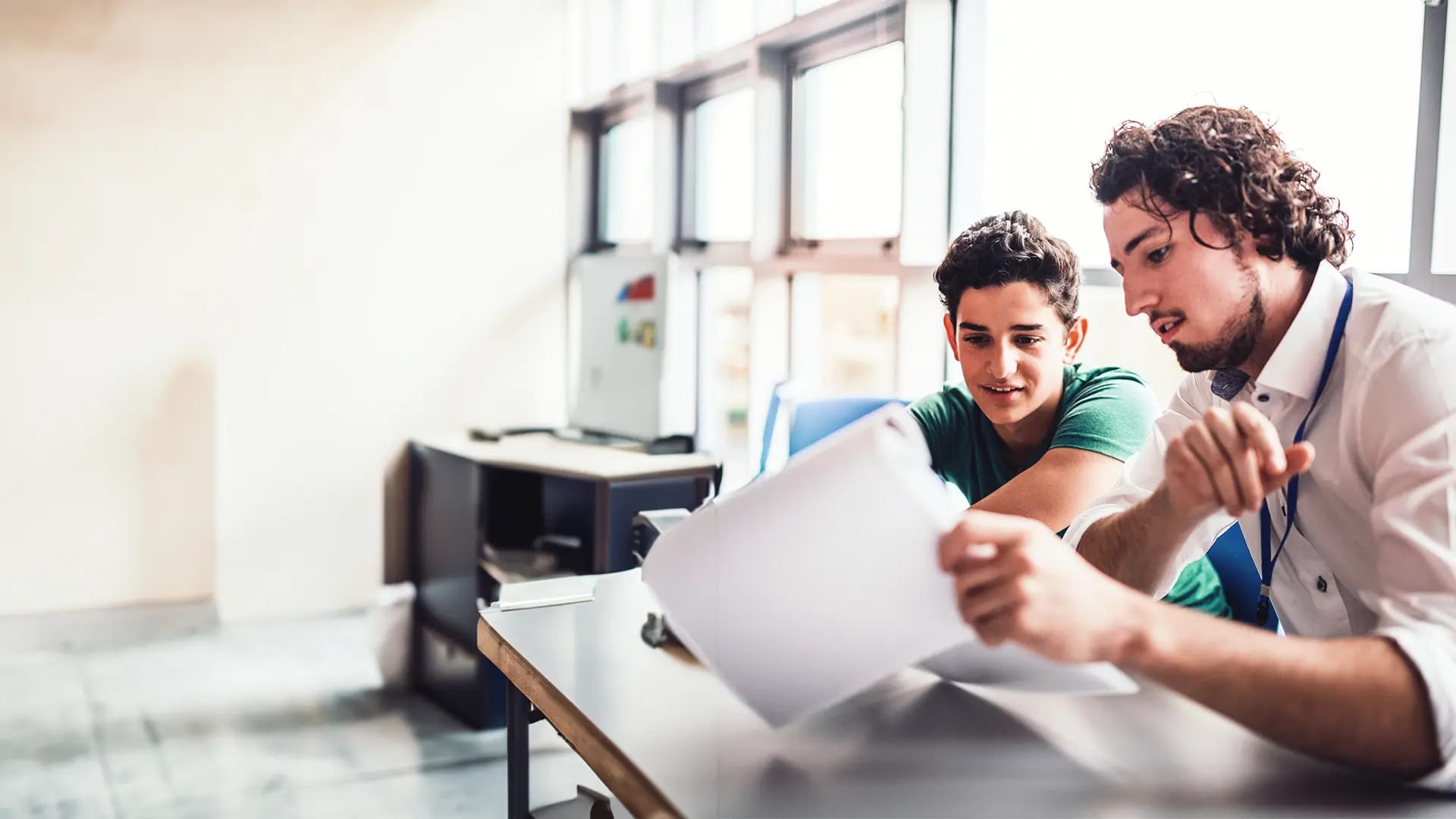 Titelbild zum Artikel "Beliebteste Studentenjobs": Student gibt einem Teenager Nachhilfe im Klassenzimmer