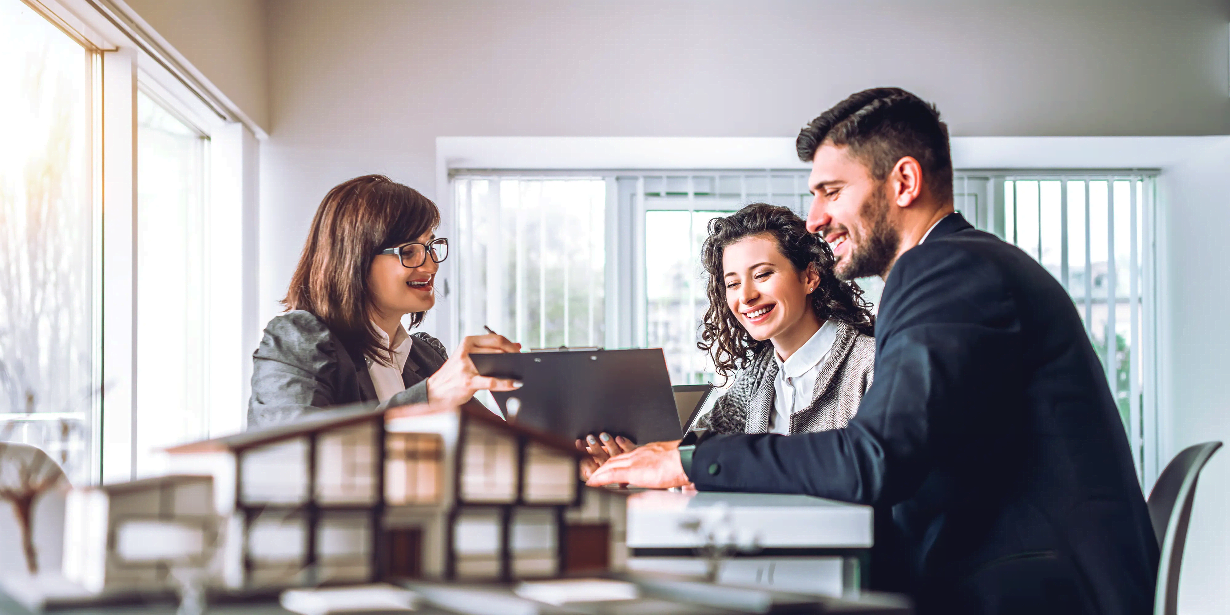 Titelbild der Infoseite "Fernstudium-Immobilienmakler": Studierende sitzen am Tisch und unterhalten sich