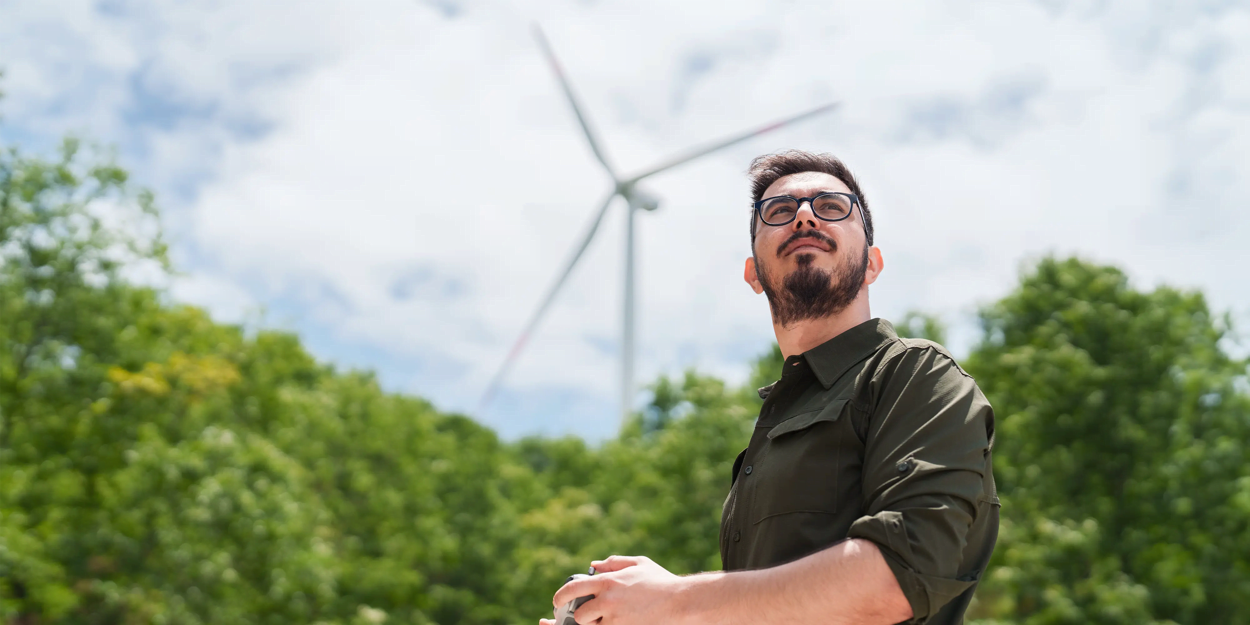 Titelbild der Infoseite "Fernstudium Sustainability Management": Studierender überprüft Windmühen