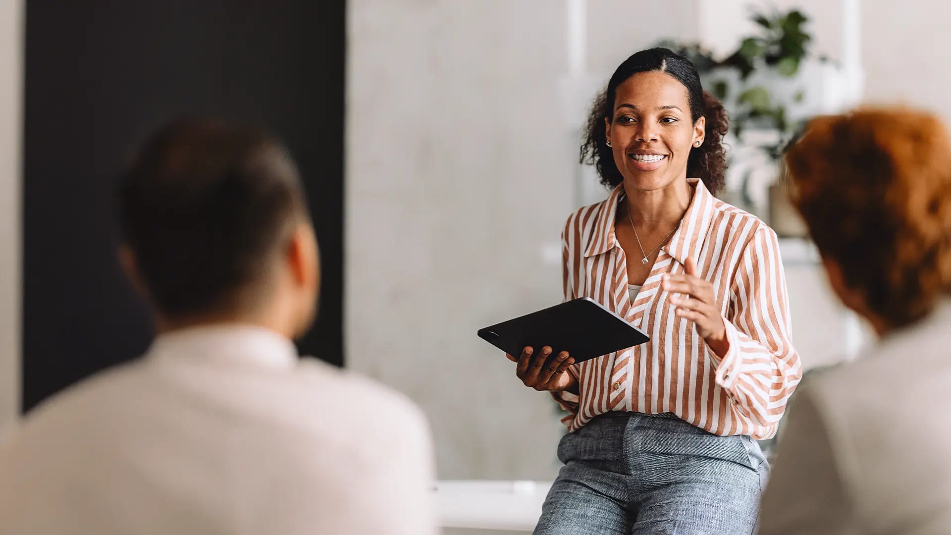 Titelbild zum Artikel: "Projektmanager:in werden: Karrierechancen und Gehalt" Frau lehnt am Tisch und hält ein Tablet in der Hand
