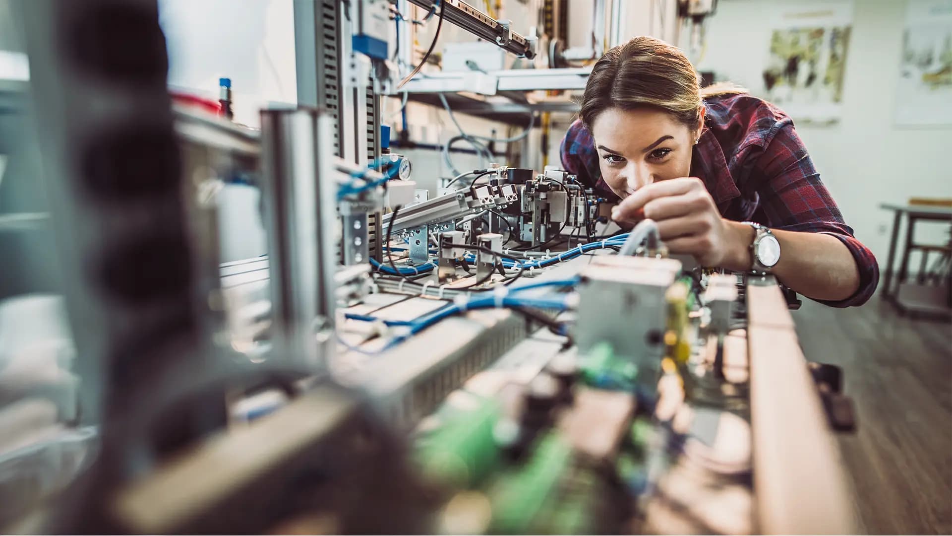 Titelbild zum Artikel "Elektrotechnik studieren ohne Abitur": Studentin arbeitet an Maschine