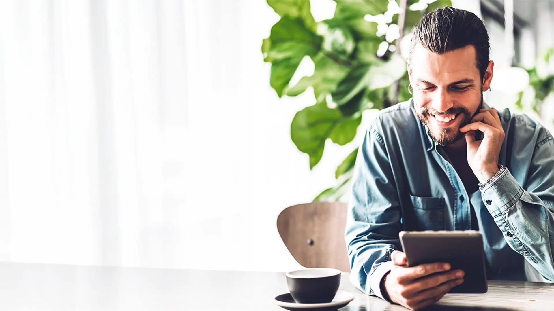 Titelbild zum Artikel "Die besten Lern-Apps fürs Studium": Student nutzt Lern-Apps fürs Studium auf dem Tablet in gemütlicher Umgebung.