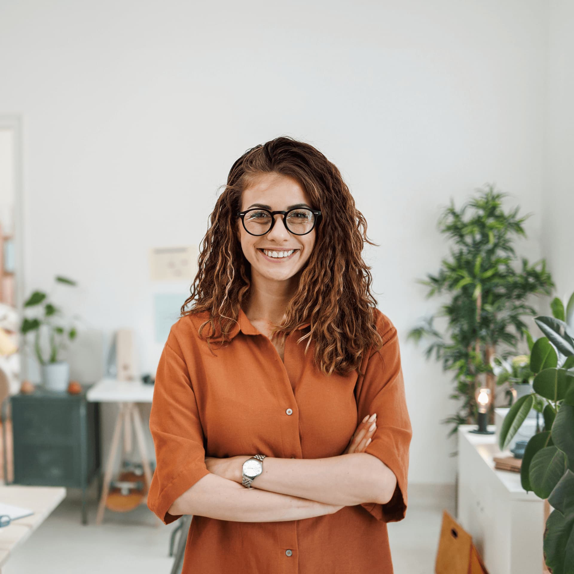 Smiling project manager standing in a home office with arms crossed.