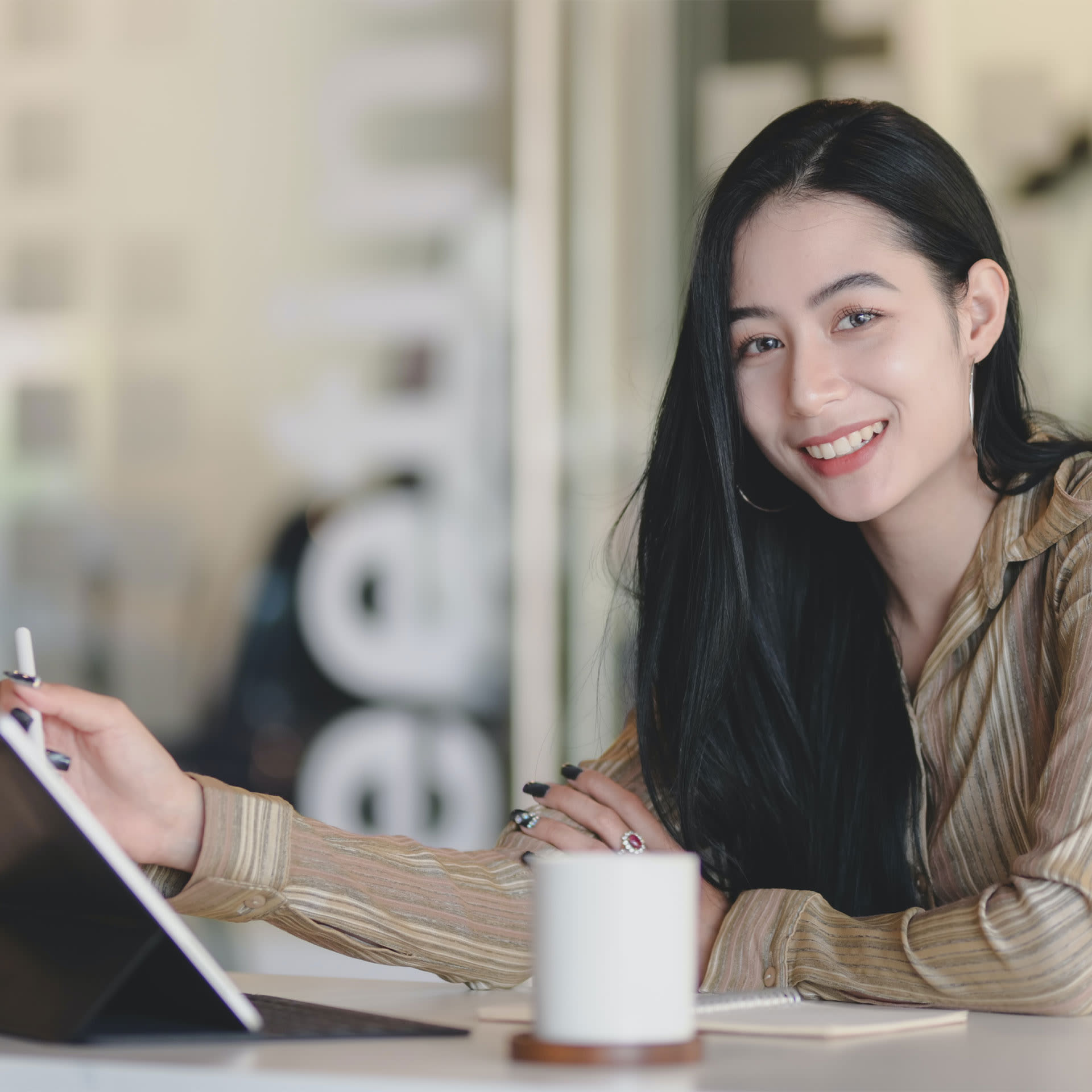 Woman smiling and holding an ipad stylus.