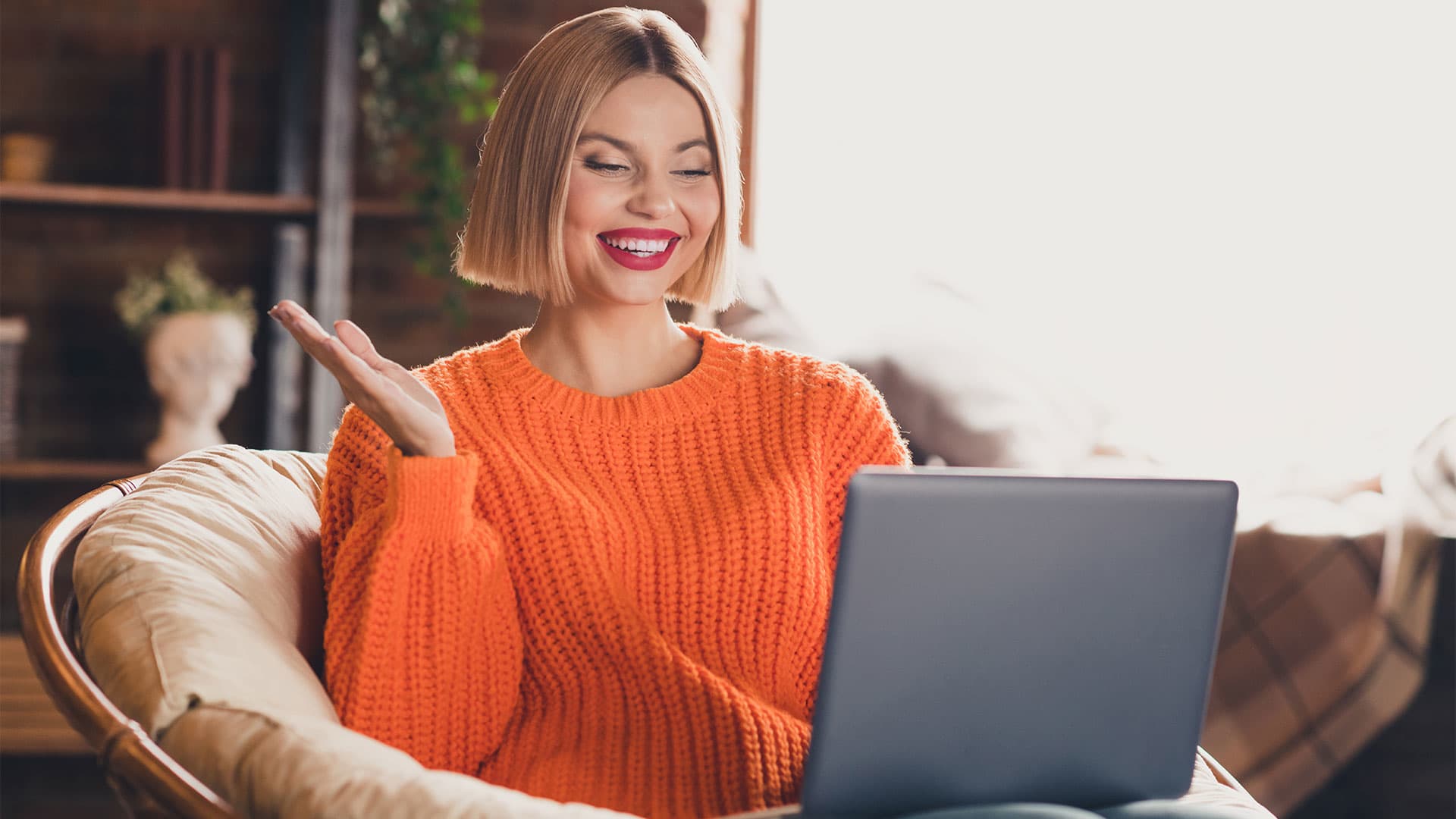 A young woman looking at her laptop and smiling.