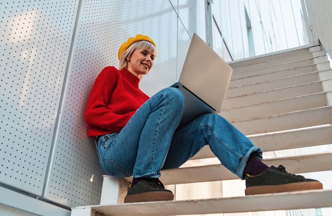 Titelbild für Infoseite "duales Studium ohne Abitur": Studentin sitzt auf Trette am Laptop