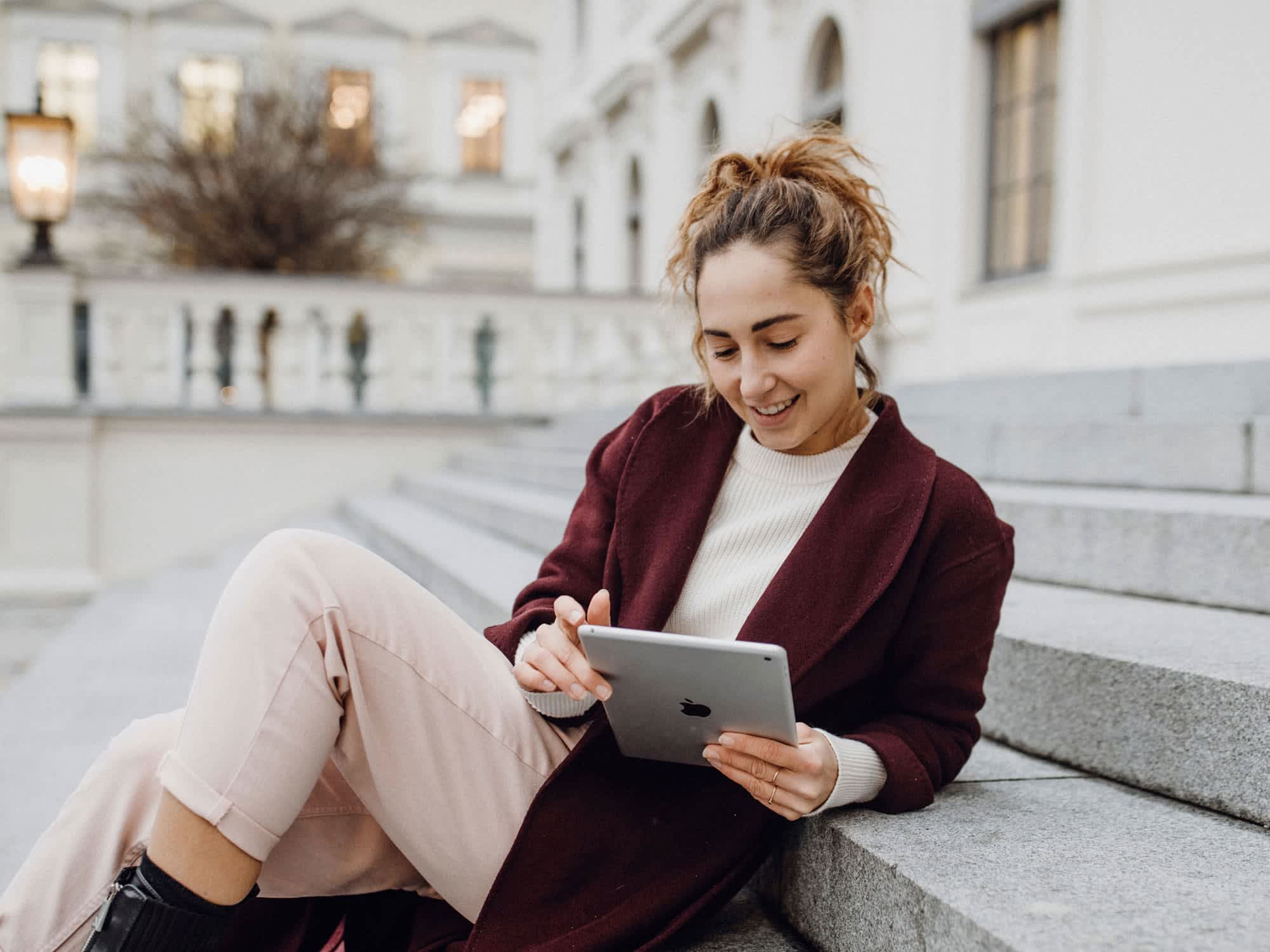 Titelbild der Infoseite "Duales Studium Rheinland-Pfalz": Duale Studentin aus Rheinland-Pfalz sitzt auf einer Treppe und schaut auf ihr Tablet