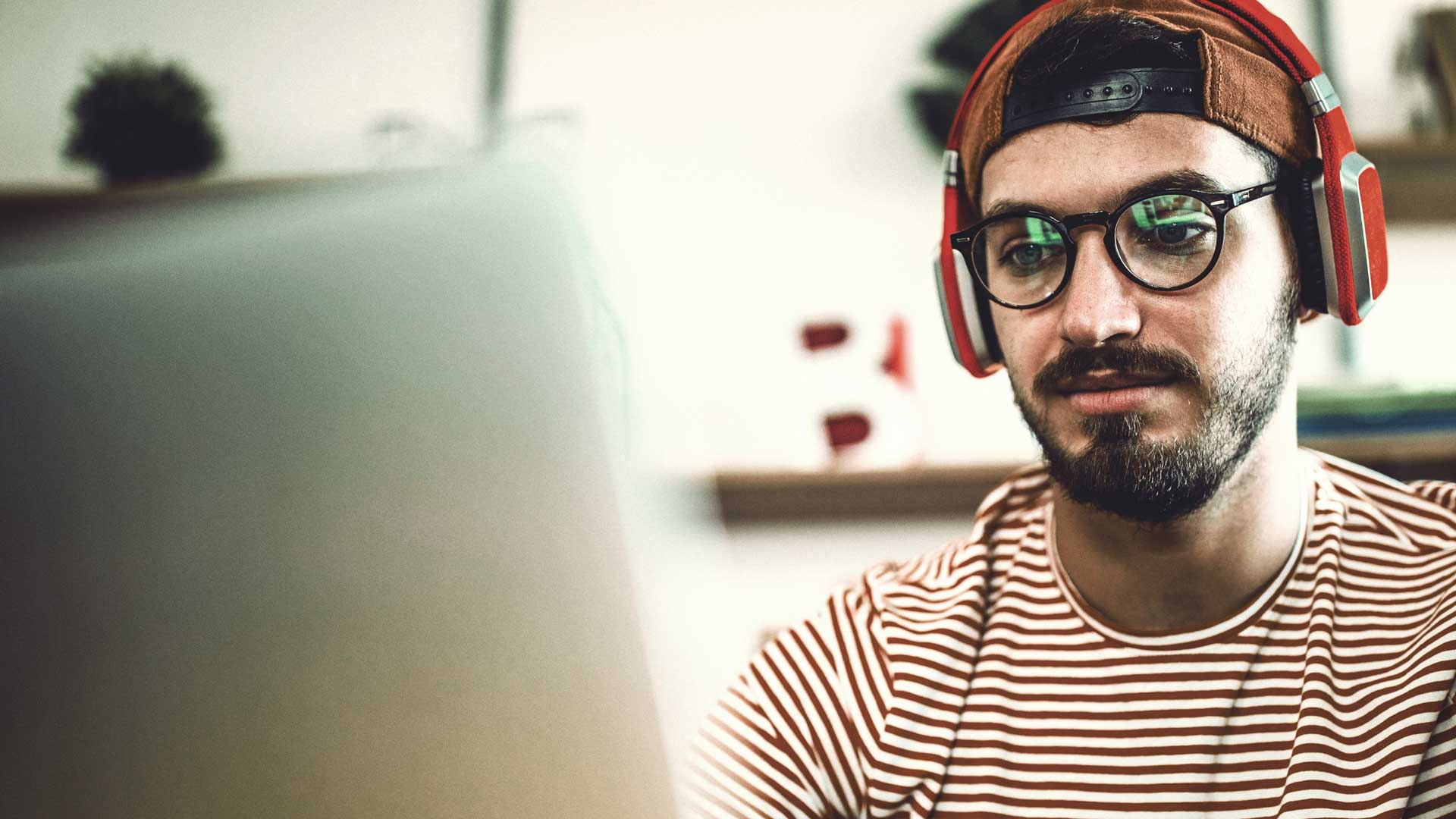 Student mit Kopfhörern schaut konzentriert auf Bildschirm