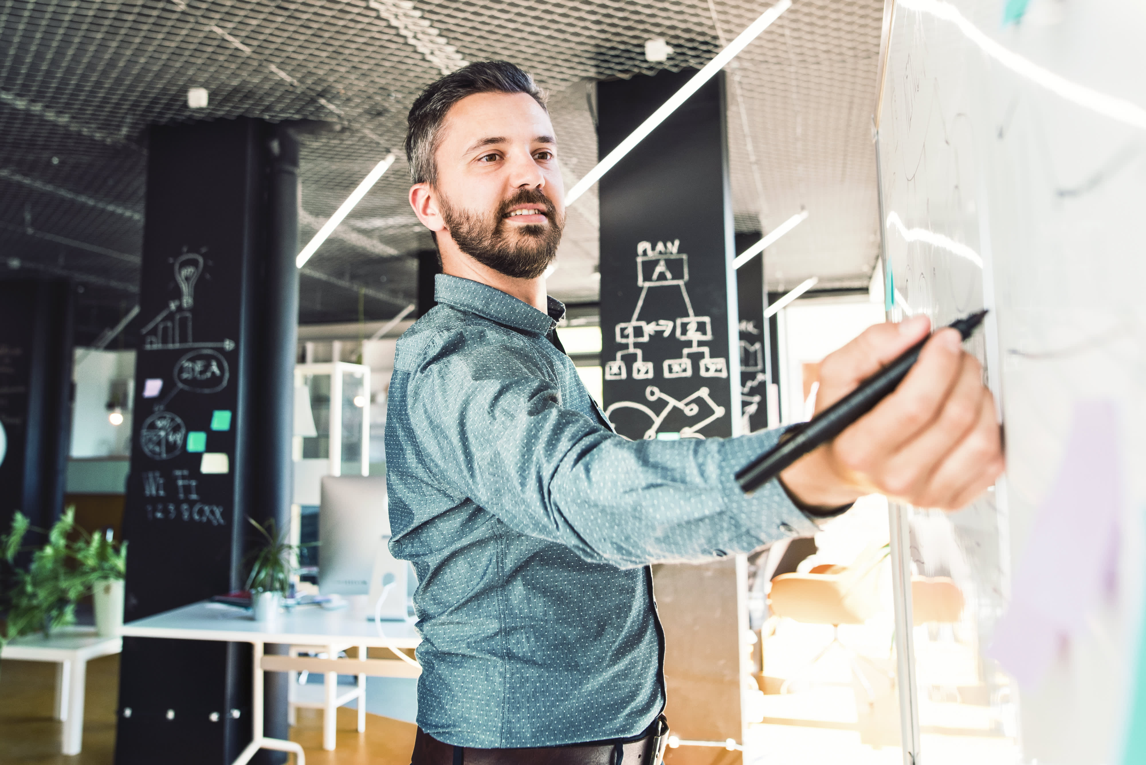 Titelbild für Artikel “Startup gründen”: Student skizziert an einer Tafel Ideen für sein Startup