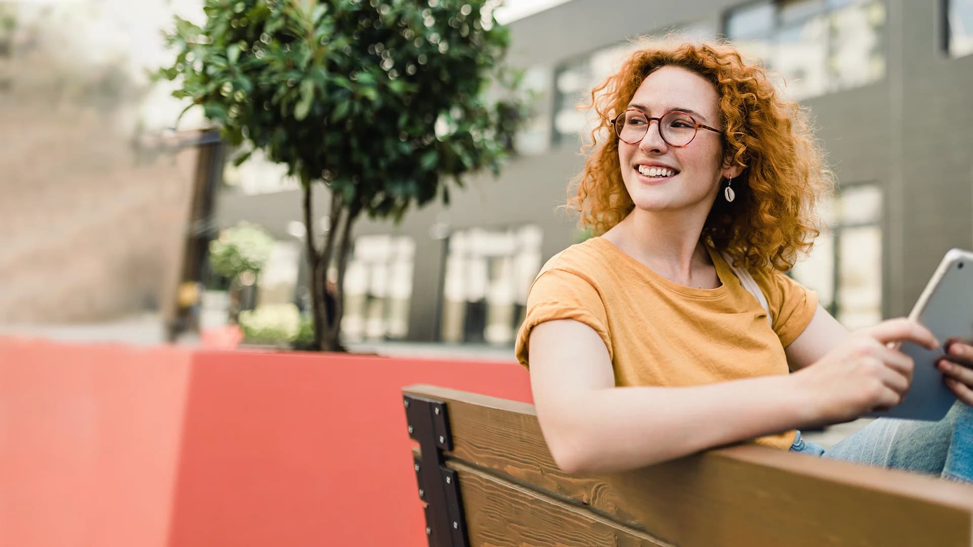 Titelbild zum Artikel "Studiengänge ohne NC": Studentin sitzt mit Tablet vor Campusgebäude