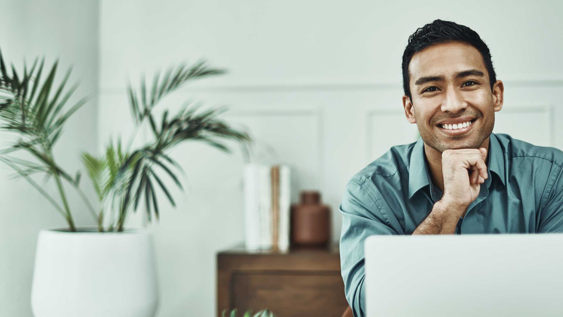 Lächelnder Mann sitzt vor Laptop